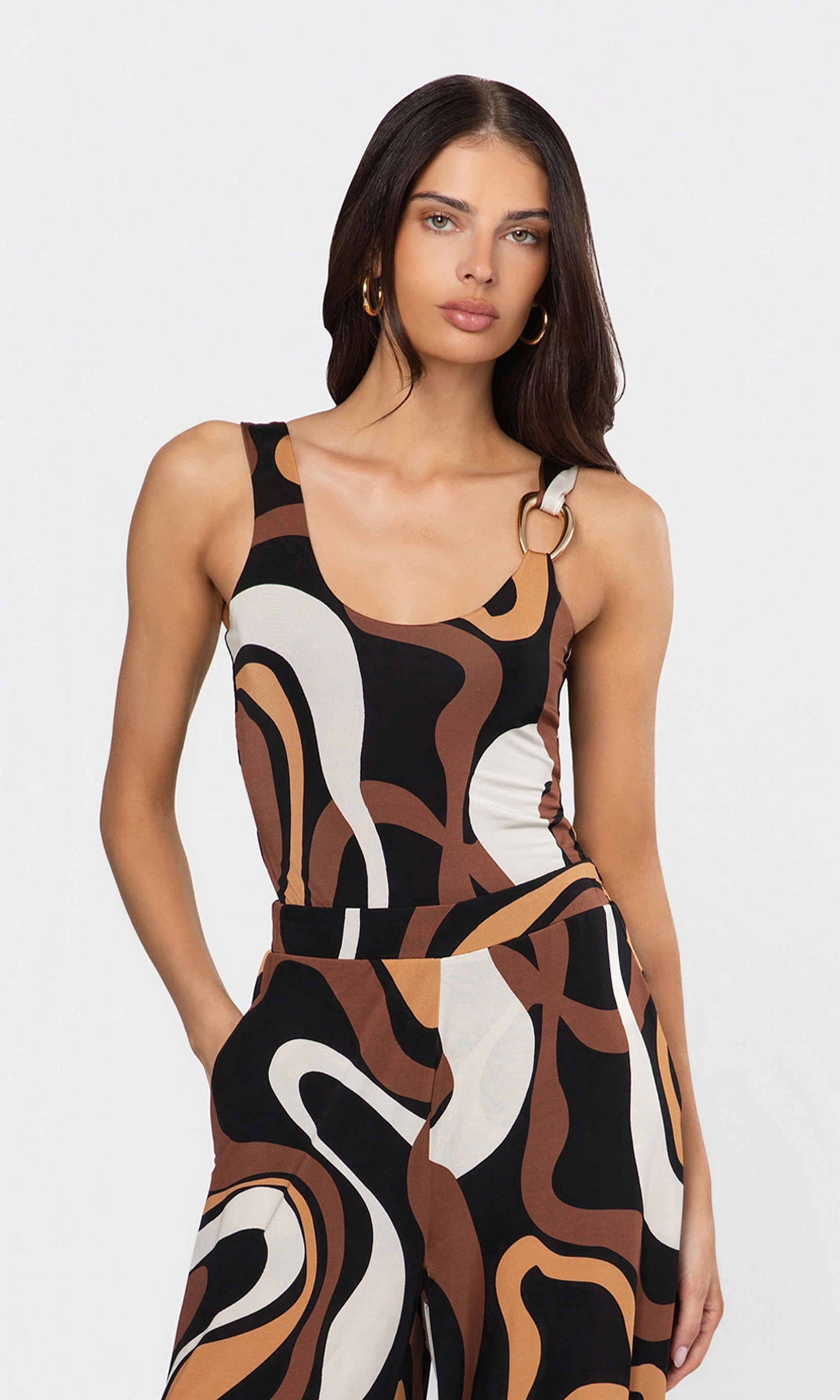 Woman wearing a sleeveless tank with abstract pattern on a white background