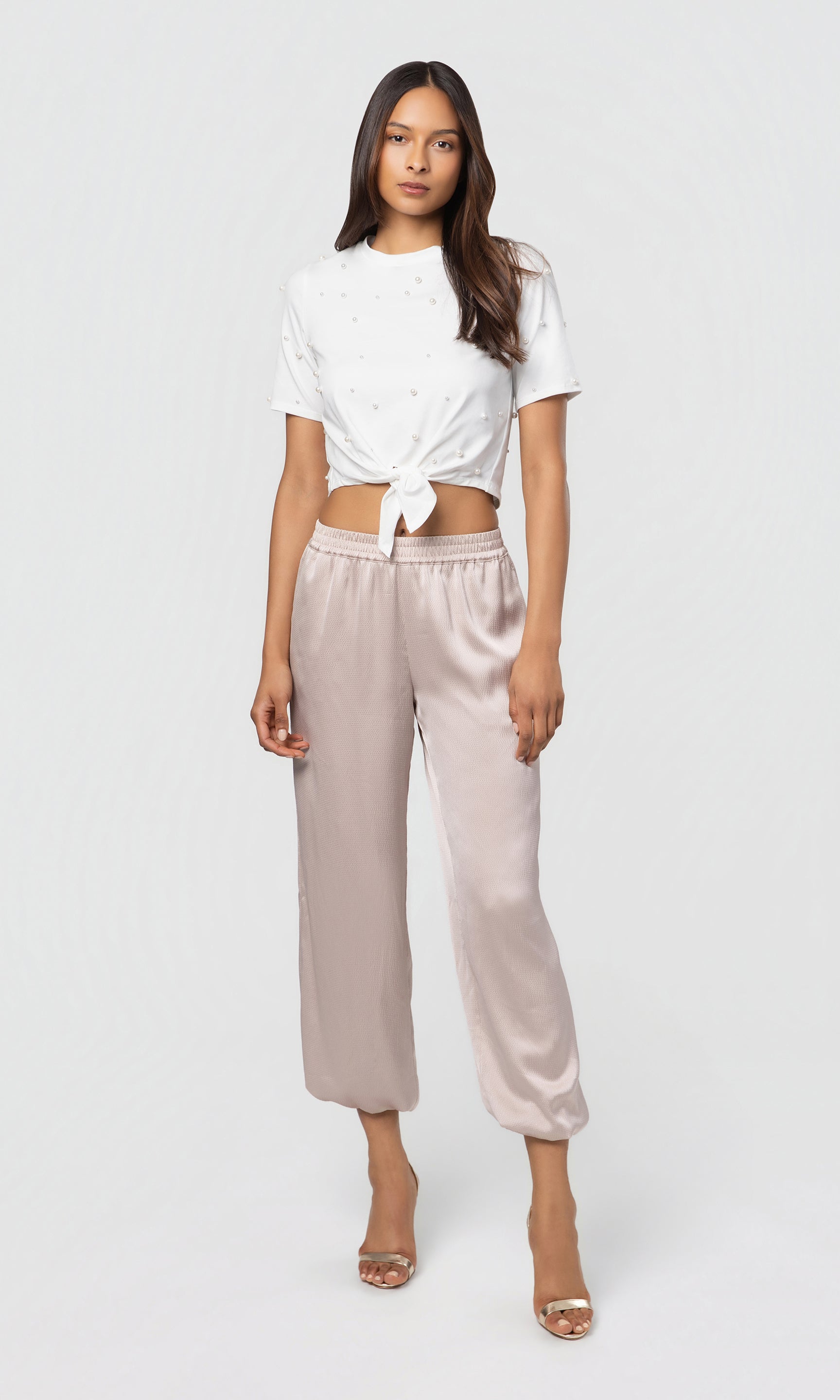 Woman wearing a white top and beige pants on a white background