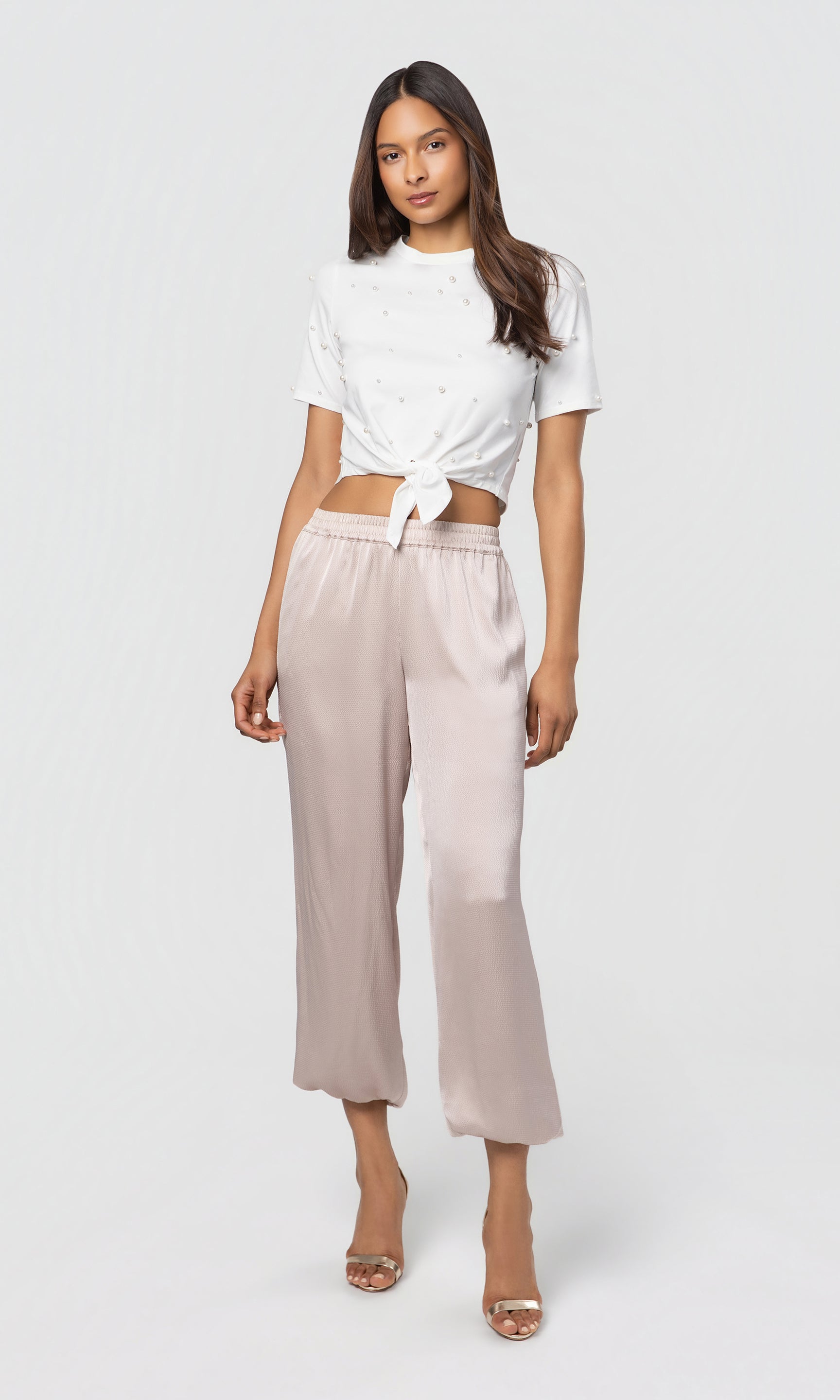 Woman wearing a white top and beige pants on a white background