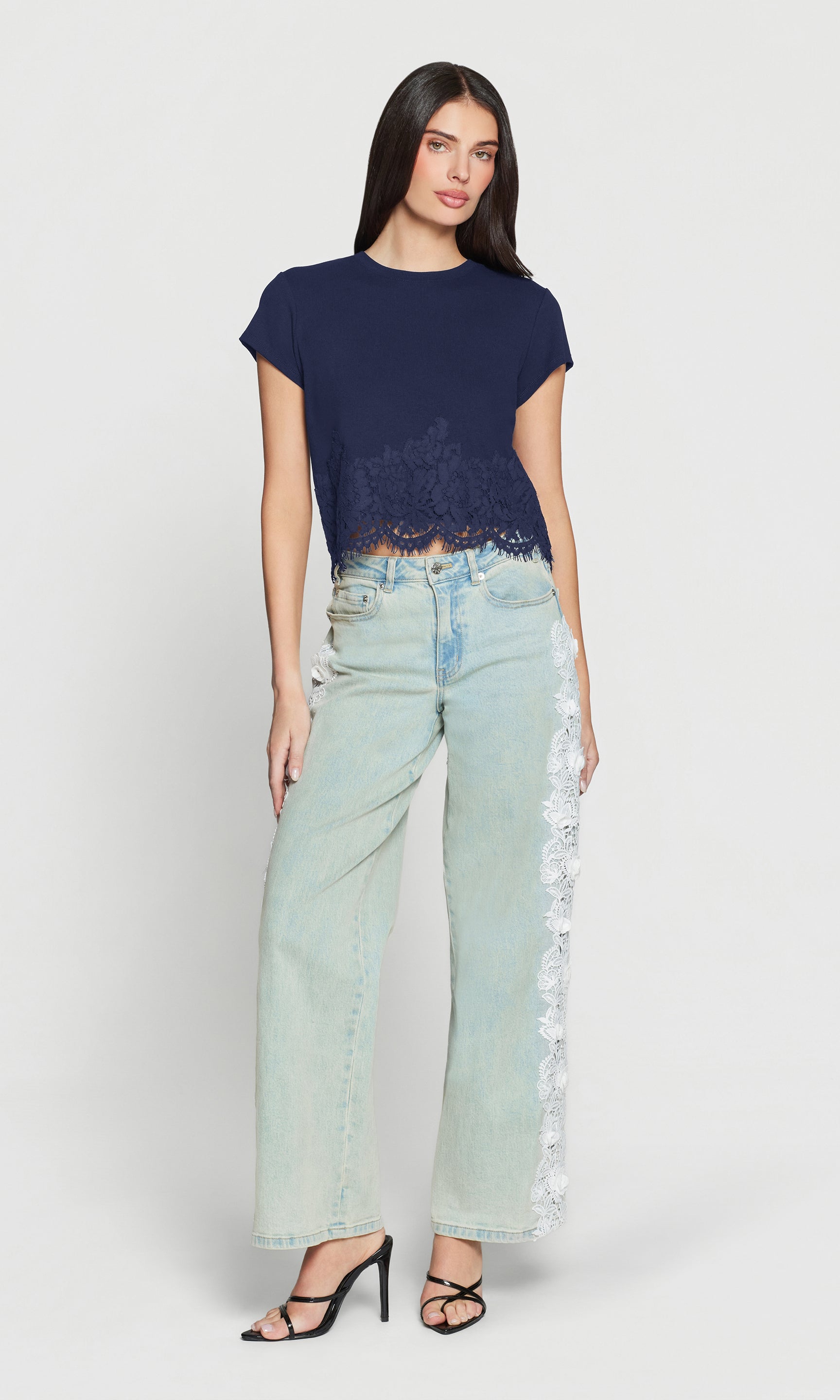 Woman wearing a navy top and light blue jeans on a white background