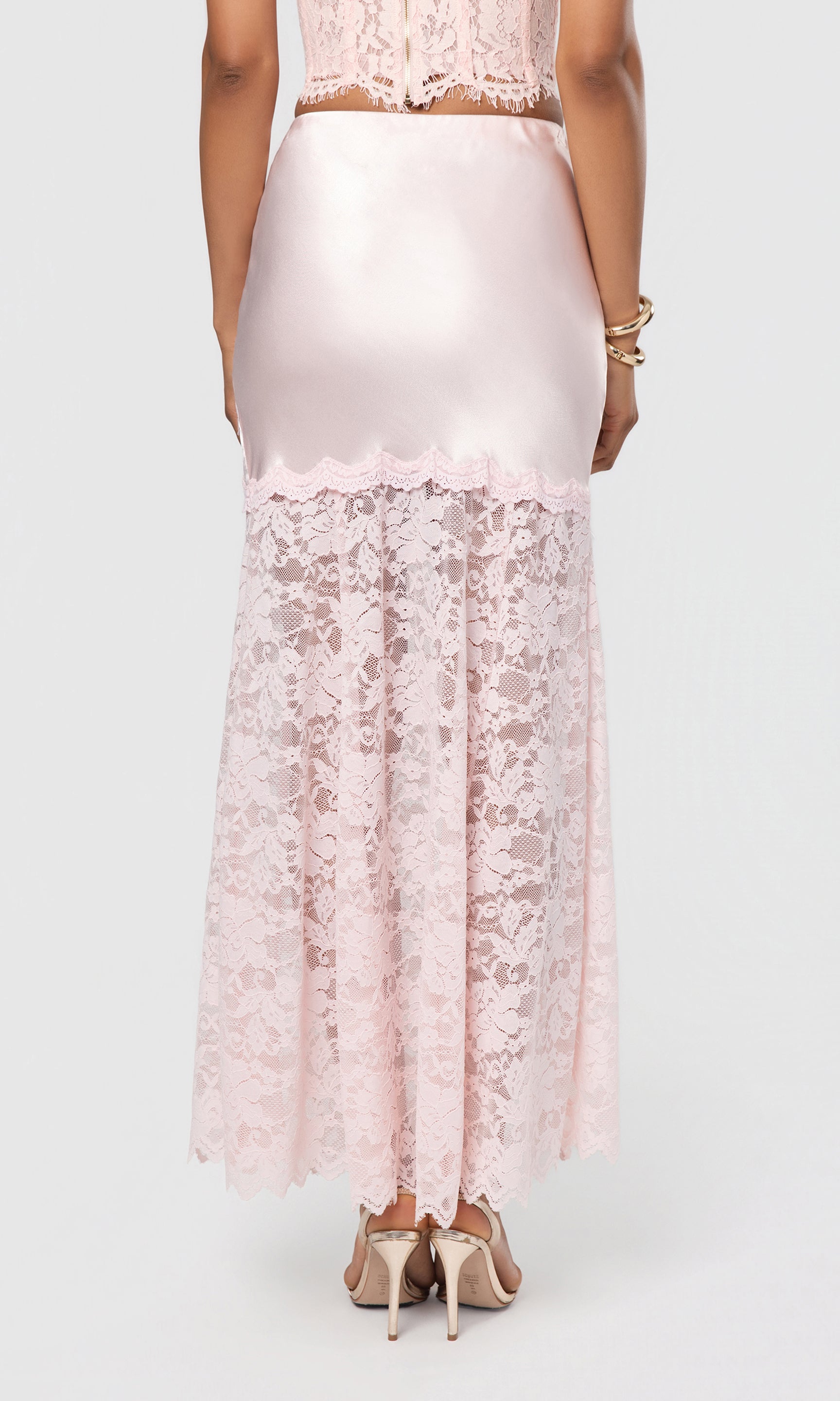 Back view of person wearing a light pink lace skirt on a white background