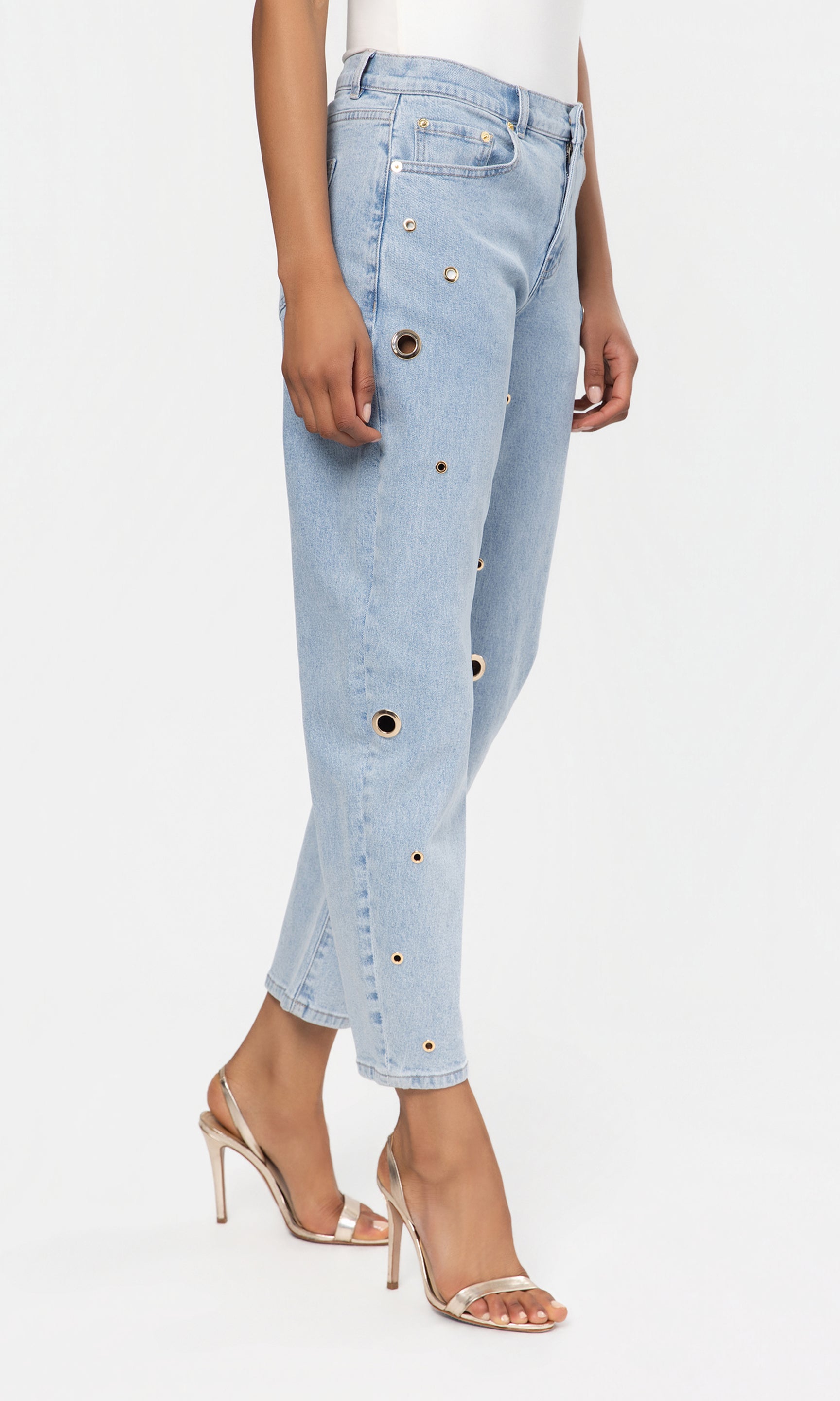 Side view of light blue jeans with button details worn by a person on a white background