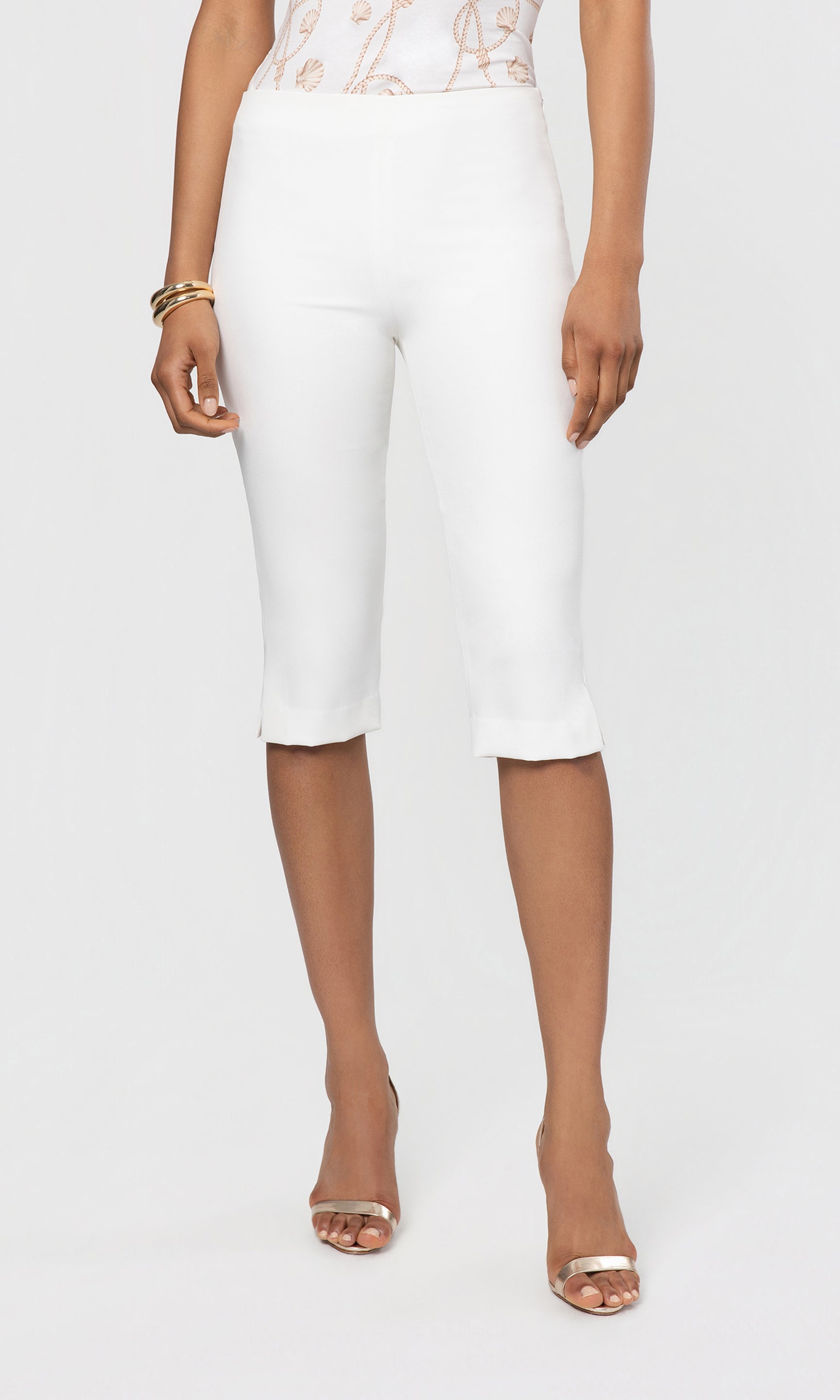 Person wearing white capri pants on a plain background