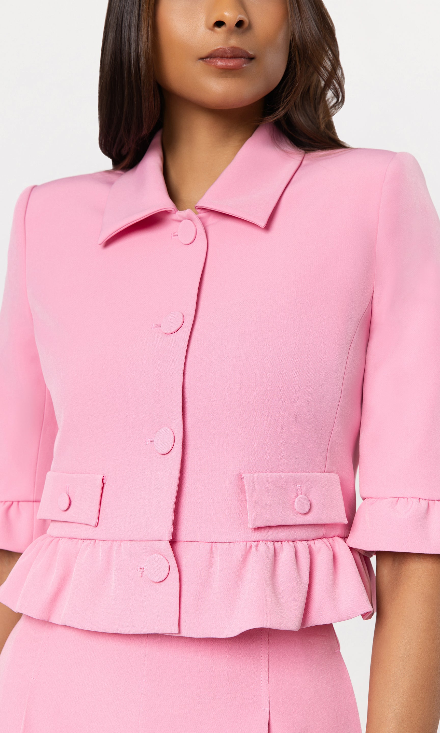 Close-up of woman wearing a pink suit with a white background