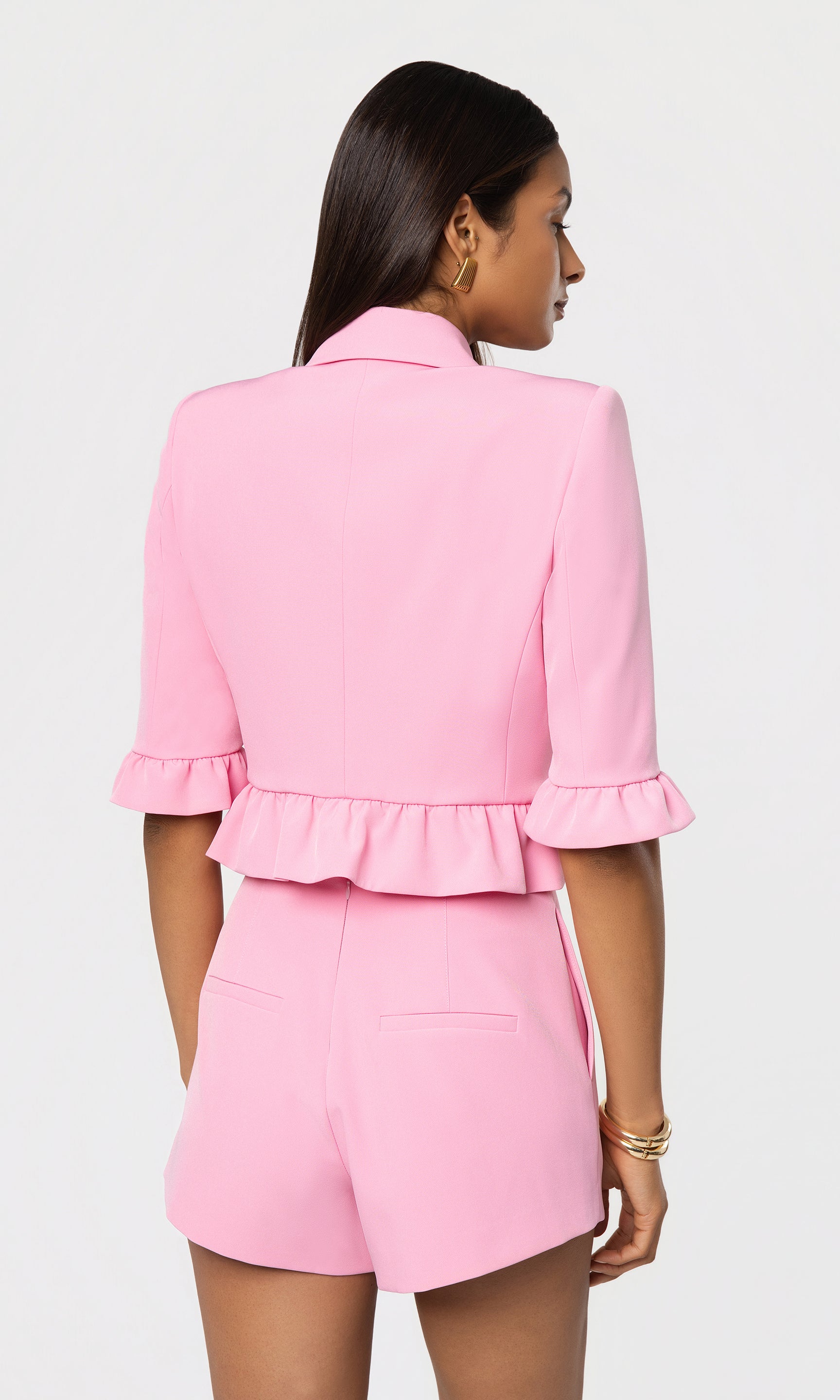 Back view of pink blazer and shorts set on a white background