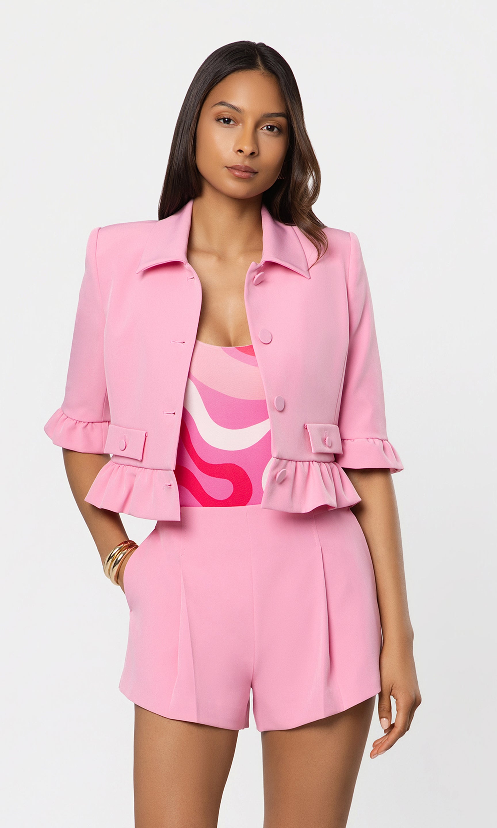 Woman wearing a pink outfit with a matching jacket on a white background