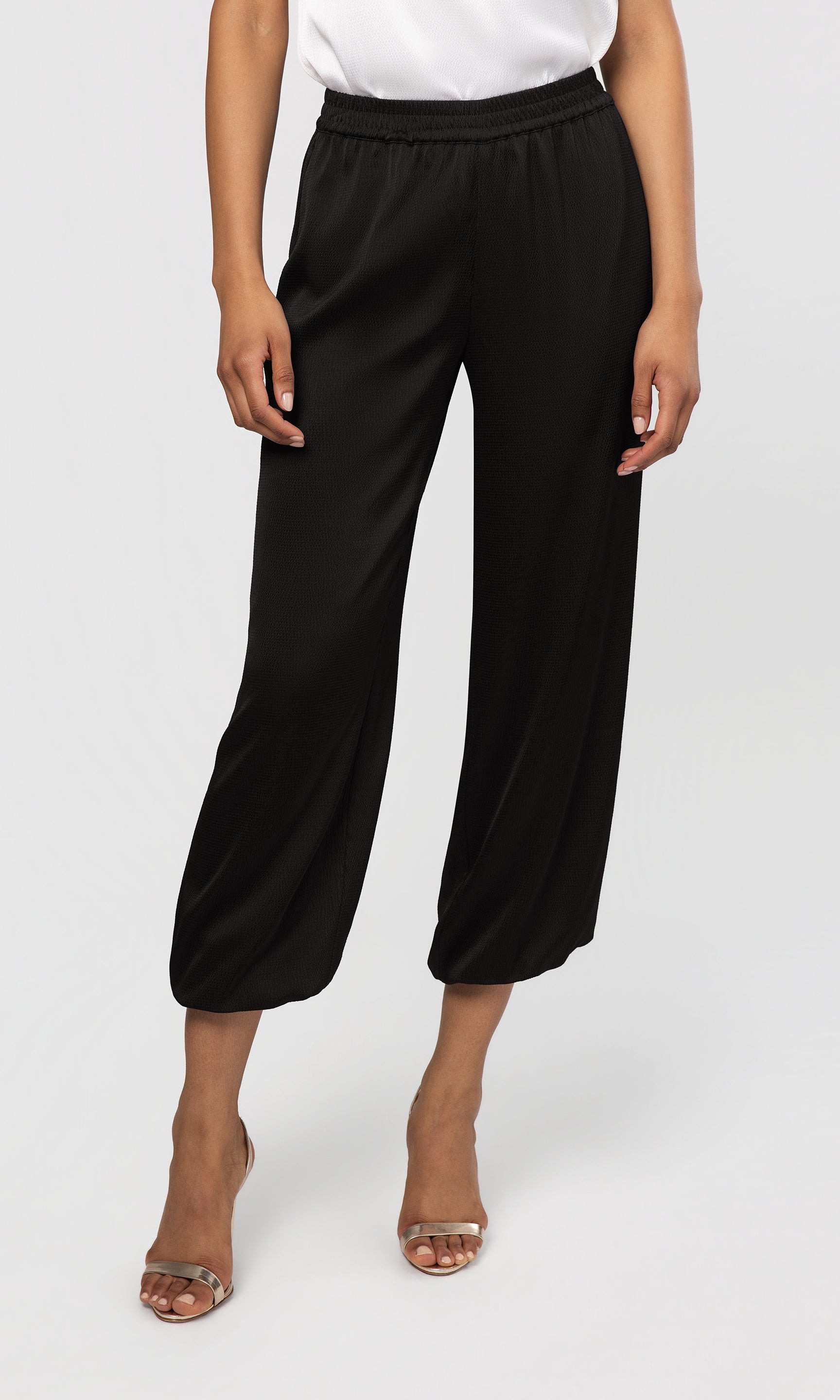 Person wearing black wide-leg pants on a white background