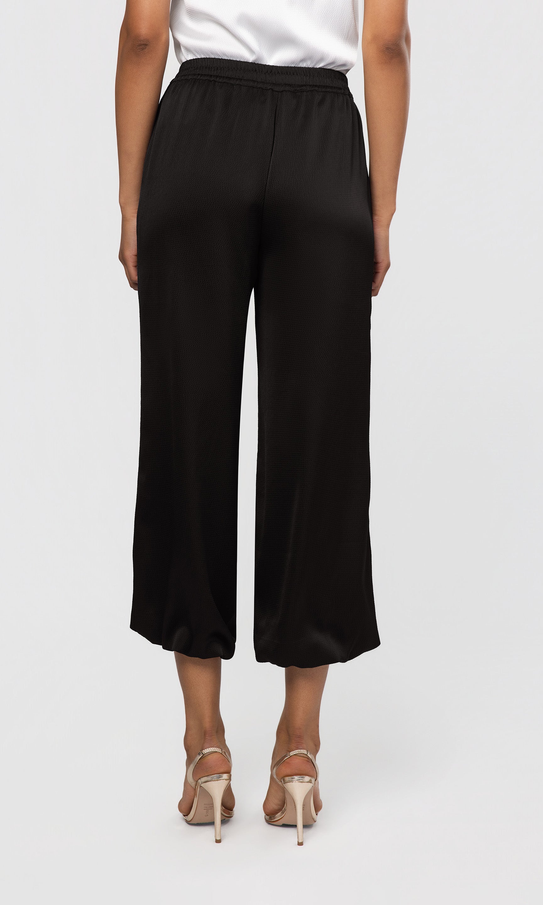 Back view of black wide-leg pants worn by a person on a white background
