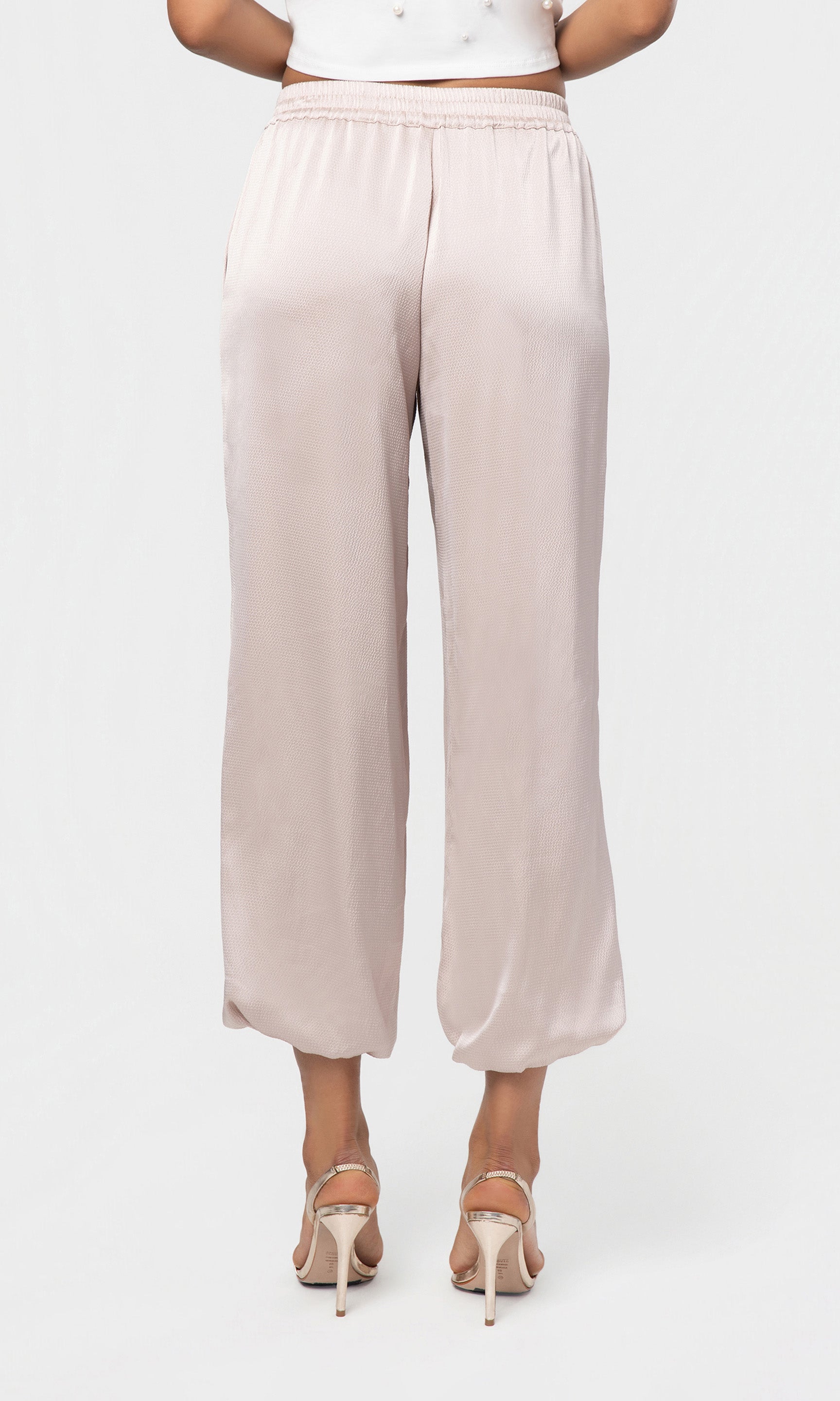 Back view of beige wide-leg pants worn by a person on a white background