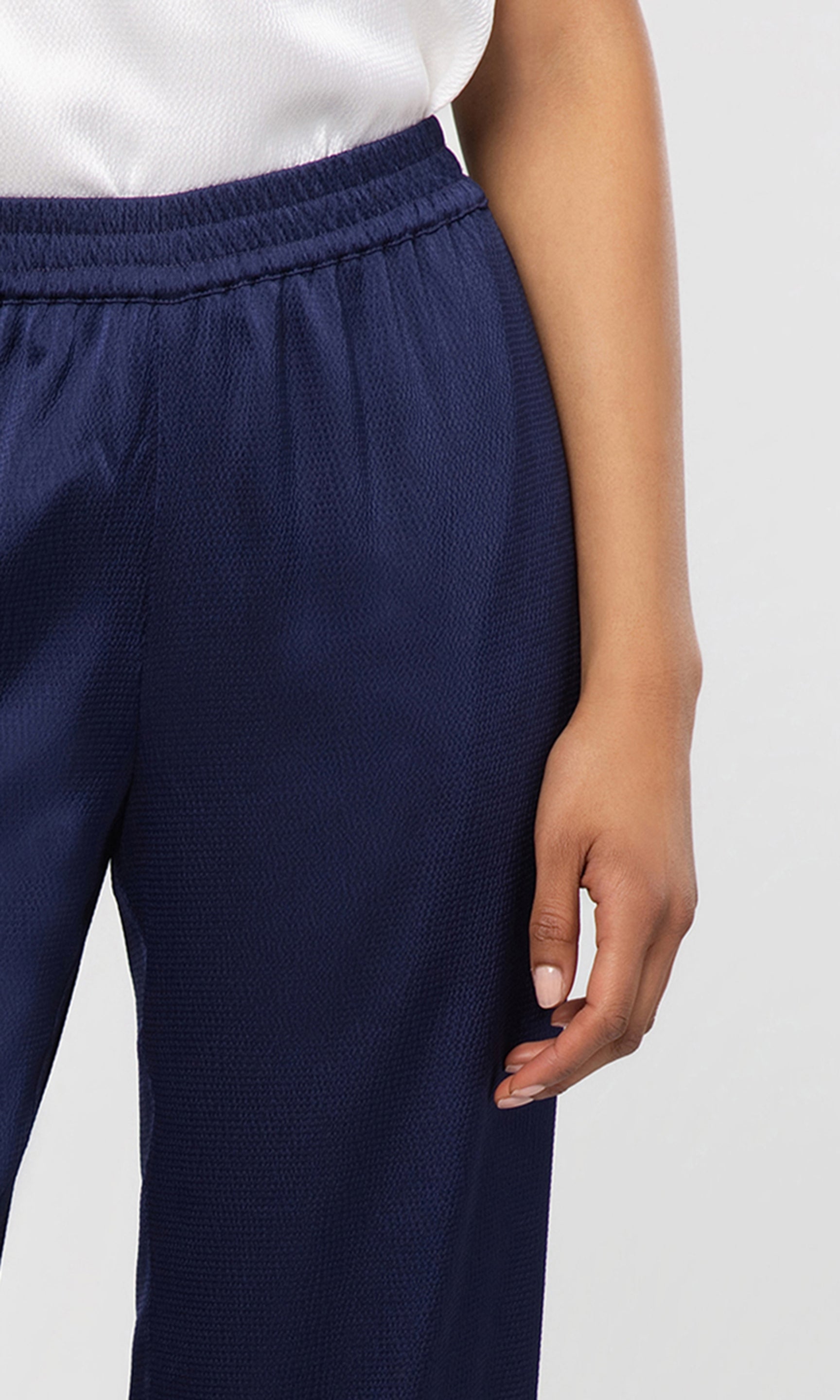 Close-up of navy blue textured pants worn by a person on a white background