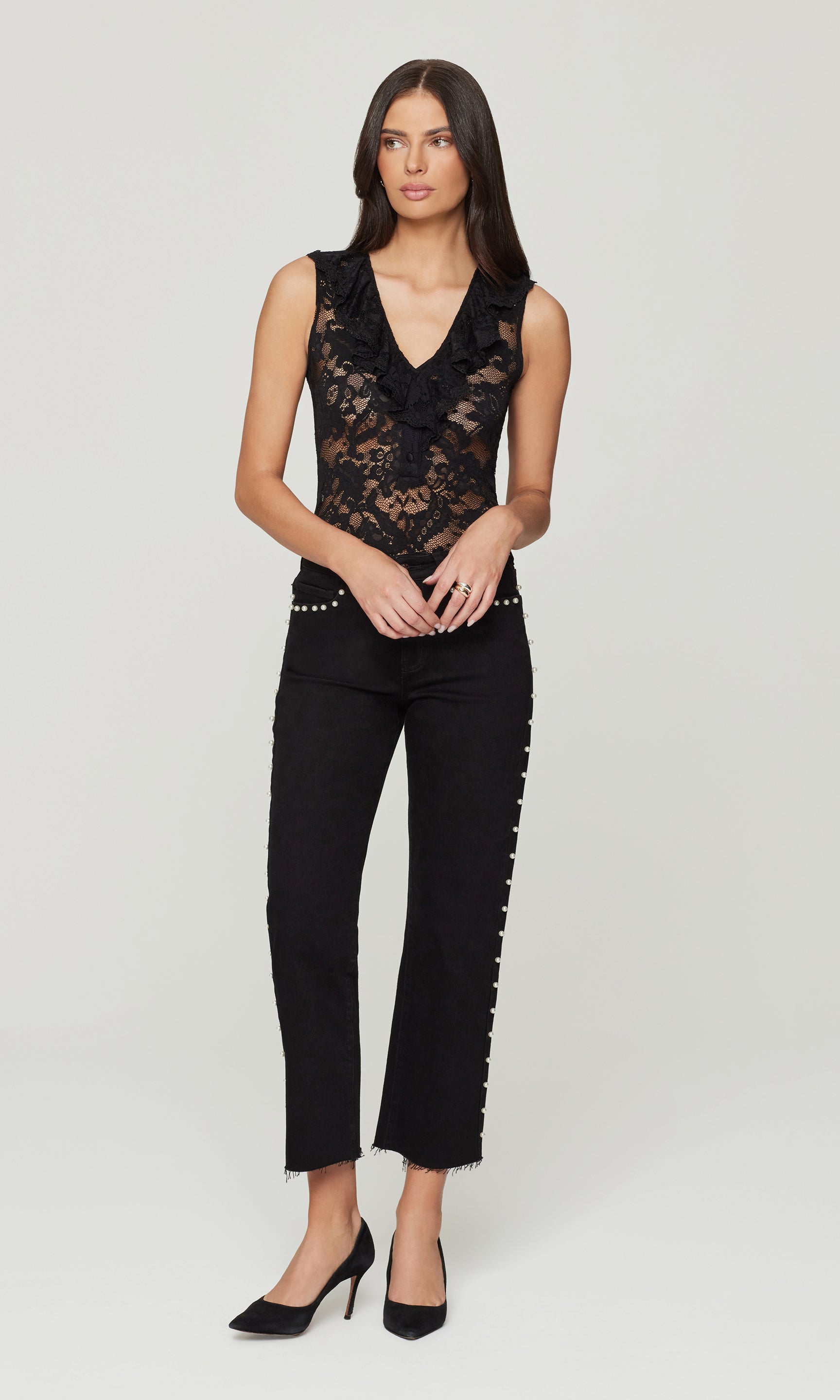 Woman wearing a black lace top and black pants on a white background