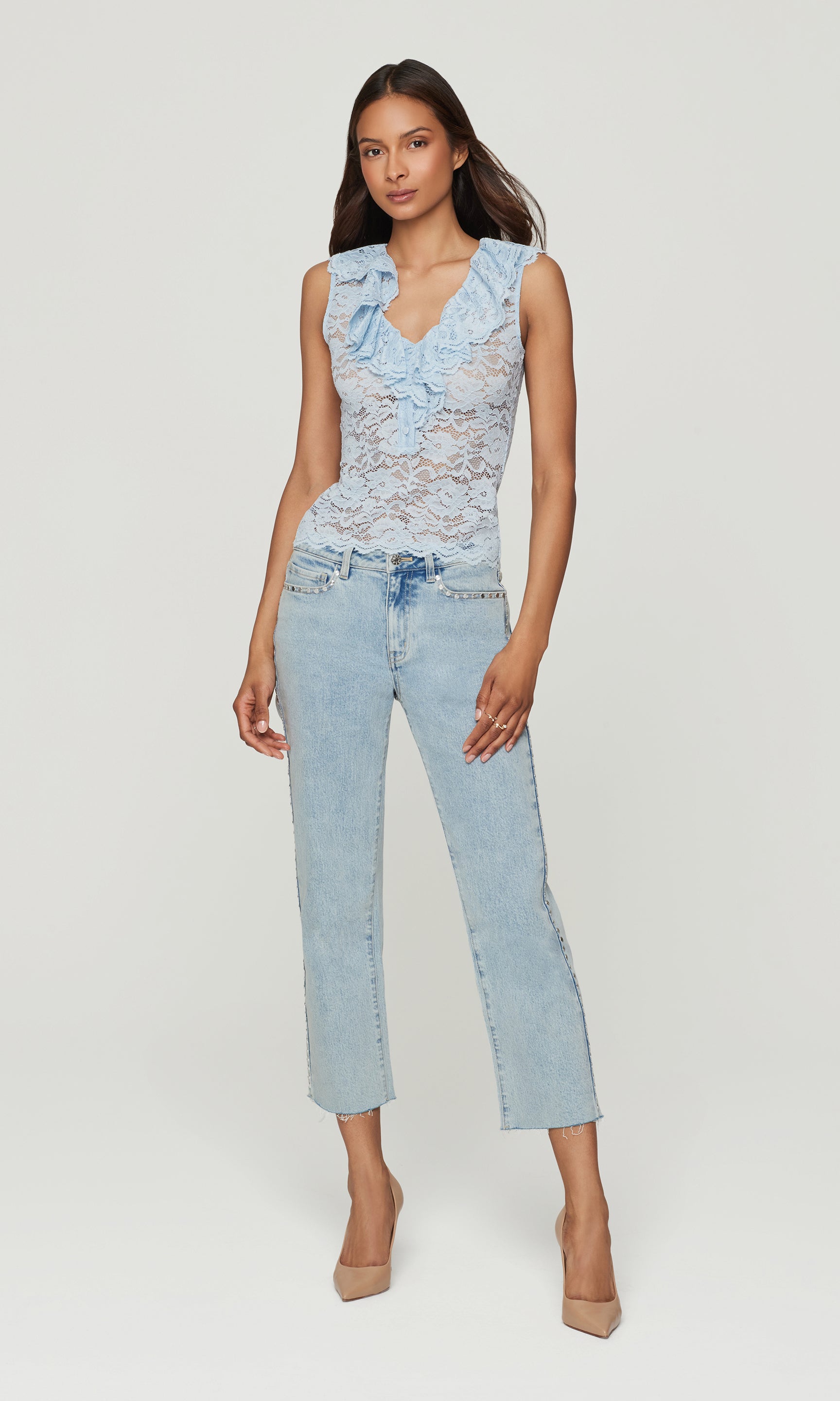 Woman wearing a light blue lace top and jeans on a white background