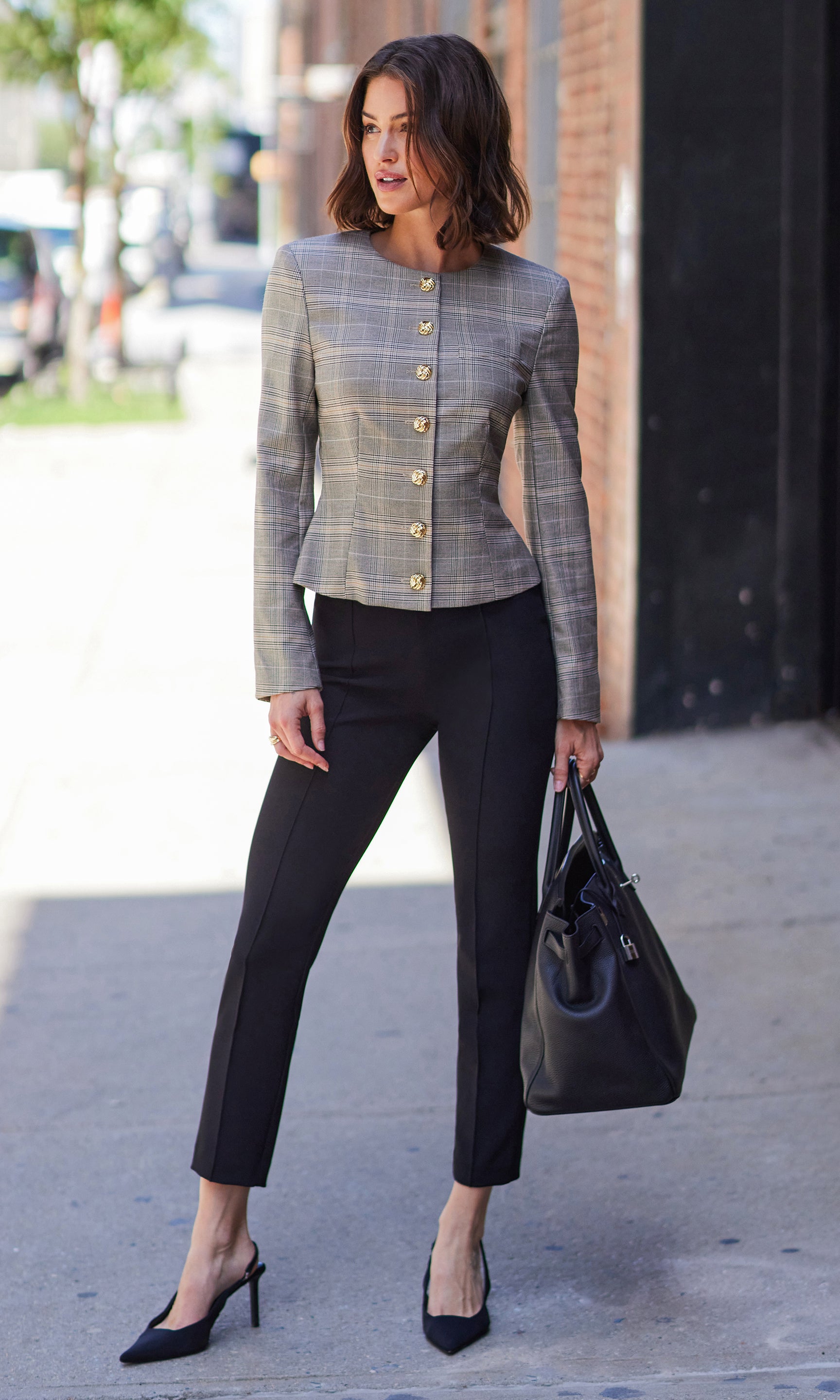 Model walking outdoors in Lonny Crepe Pants paired with a short-sleeve top and heels, carrying a black handbag.