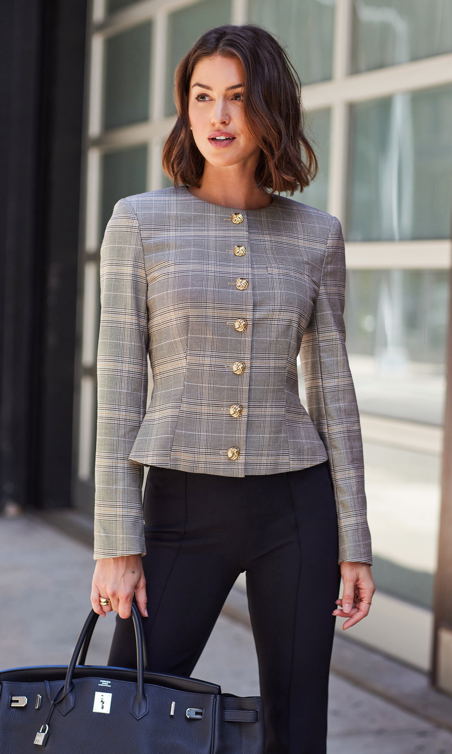 Sirus Plaid Jacket styled with black pants, captured in a front view while holding a navy handbag outdoors.