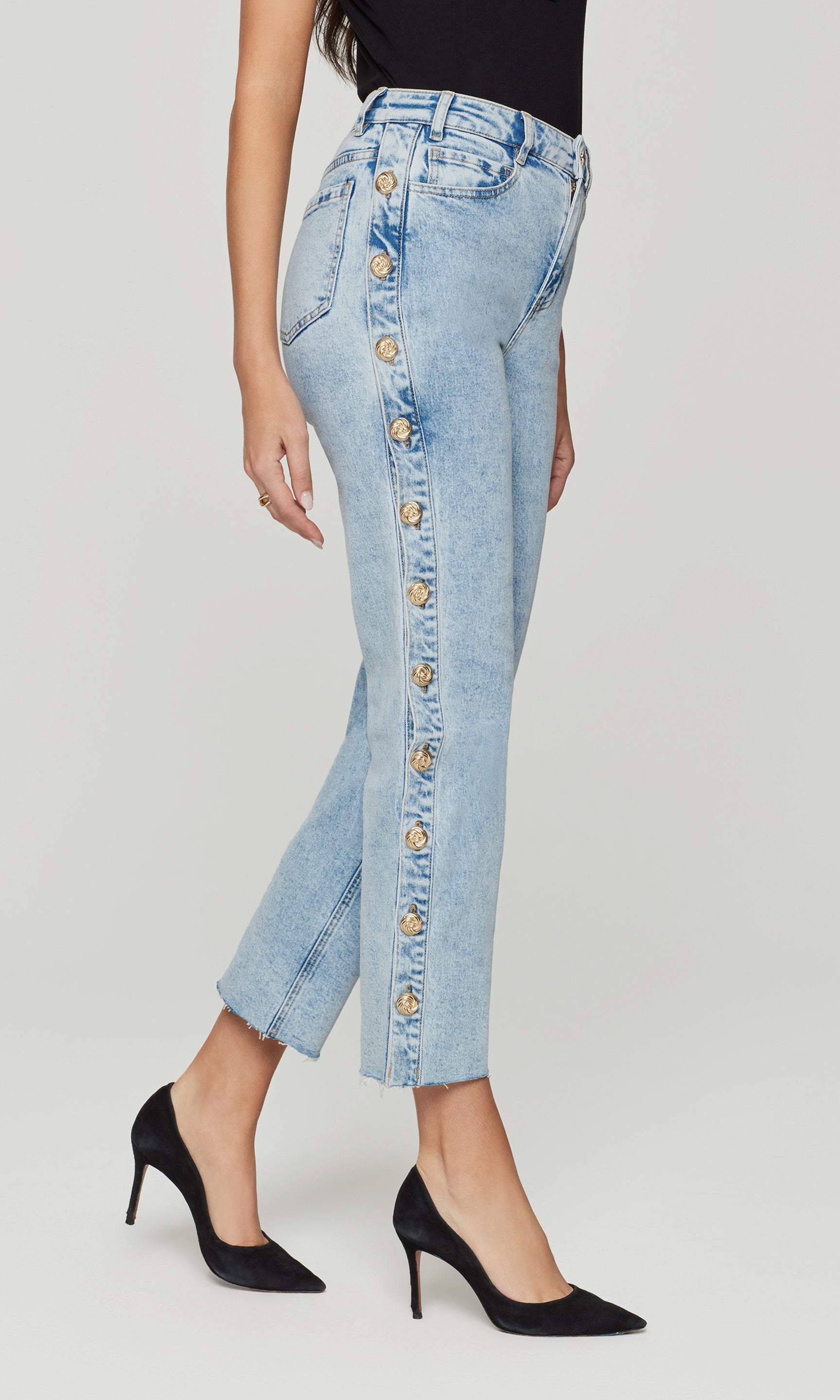 Light blue jeans with button details worn by a person on a light gray background