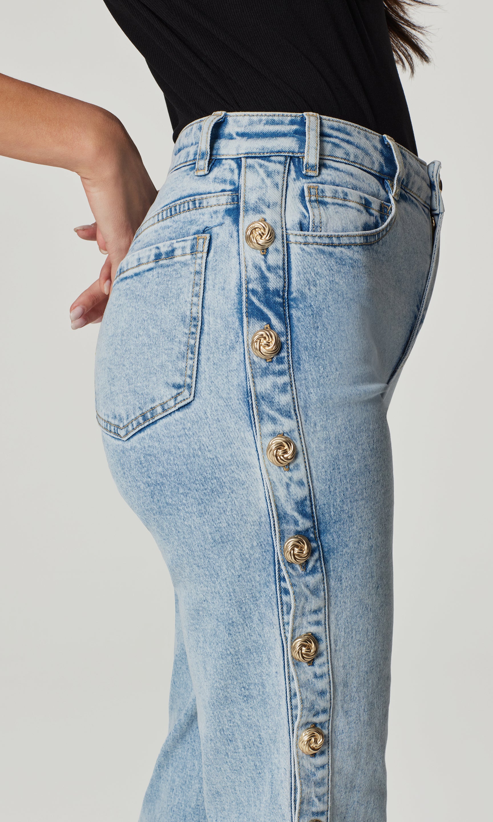 Light blue jeans with gold buttons on a plain background