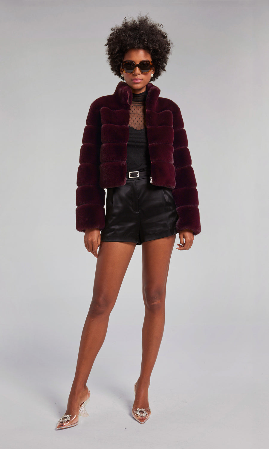 A woman models a malbec faux fur bomber coat, exuding sophistication and style in her fashionable attire.