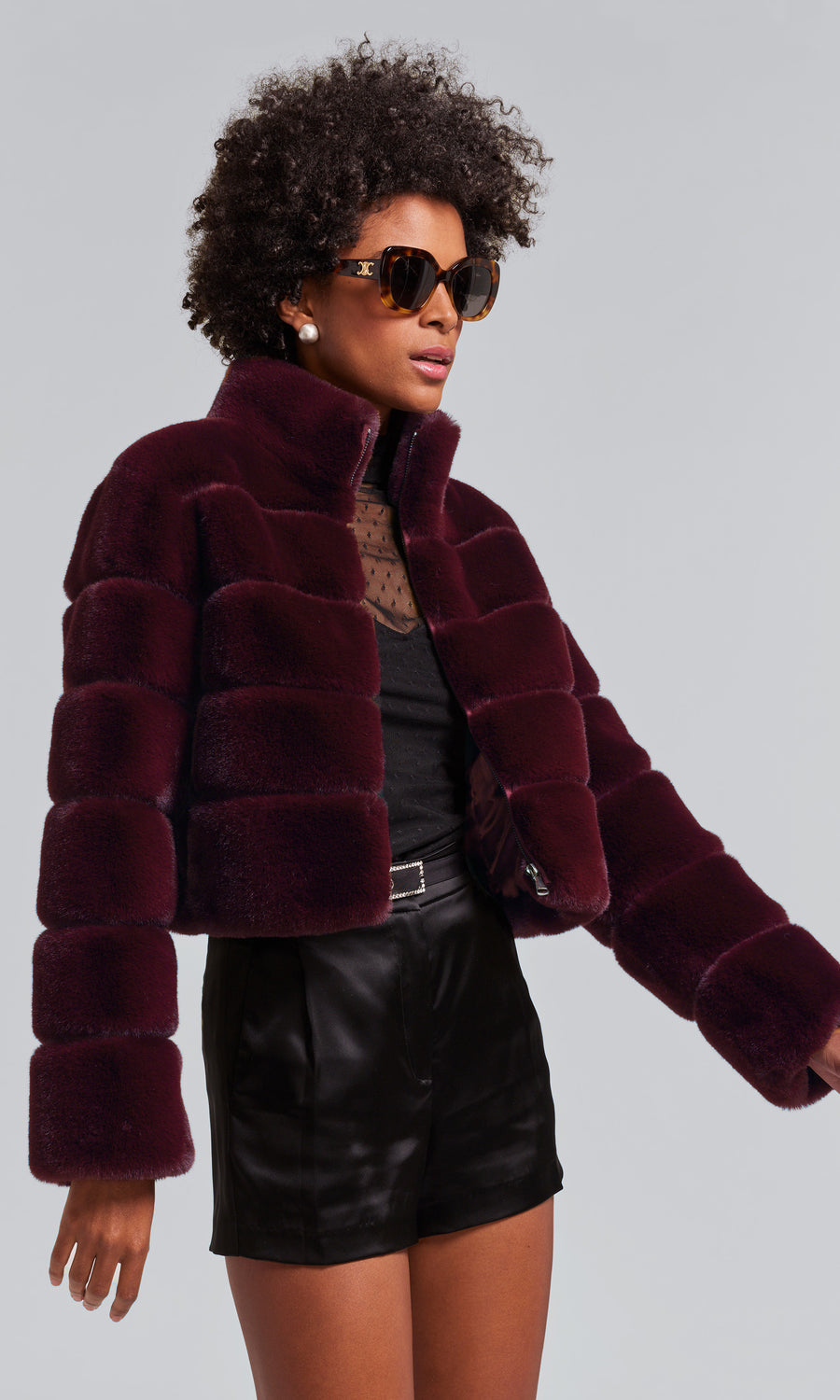 A woman models a malbec faux fur bomber coat, exuding sophistication and style in her fashionable attire.