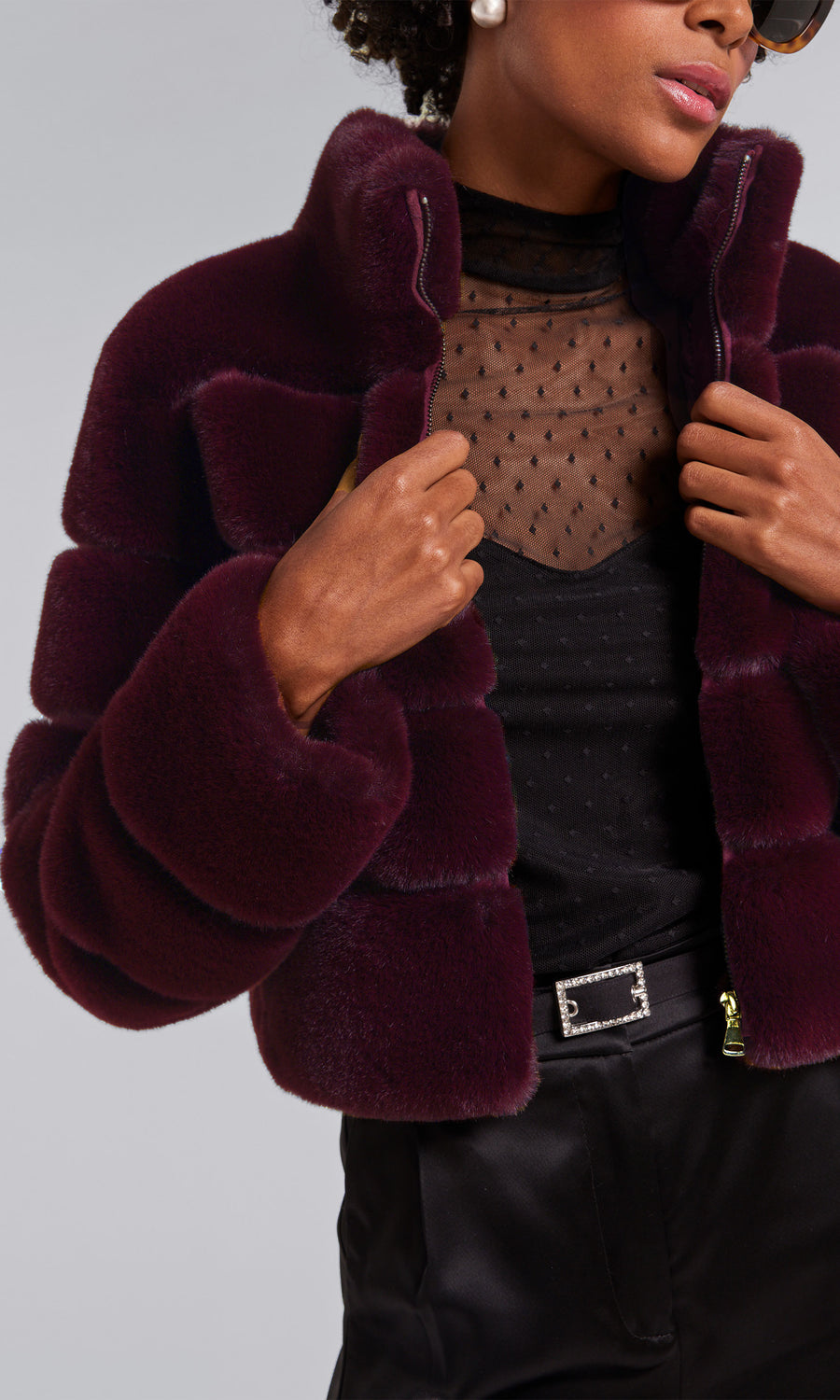 A woman models a malbec faux fur bomber coat, exuding sophistication and style in her fashionable attire.