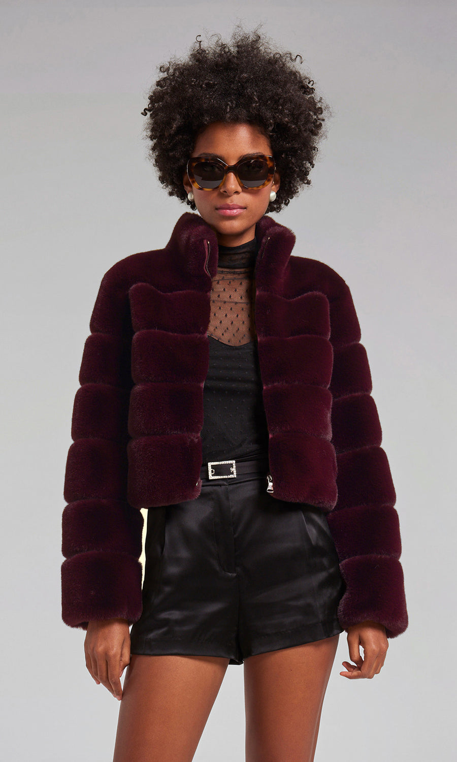 A woman models a malbec faux fur bomber coat, exuding sophistication and style in her fashionable attire.