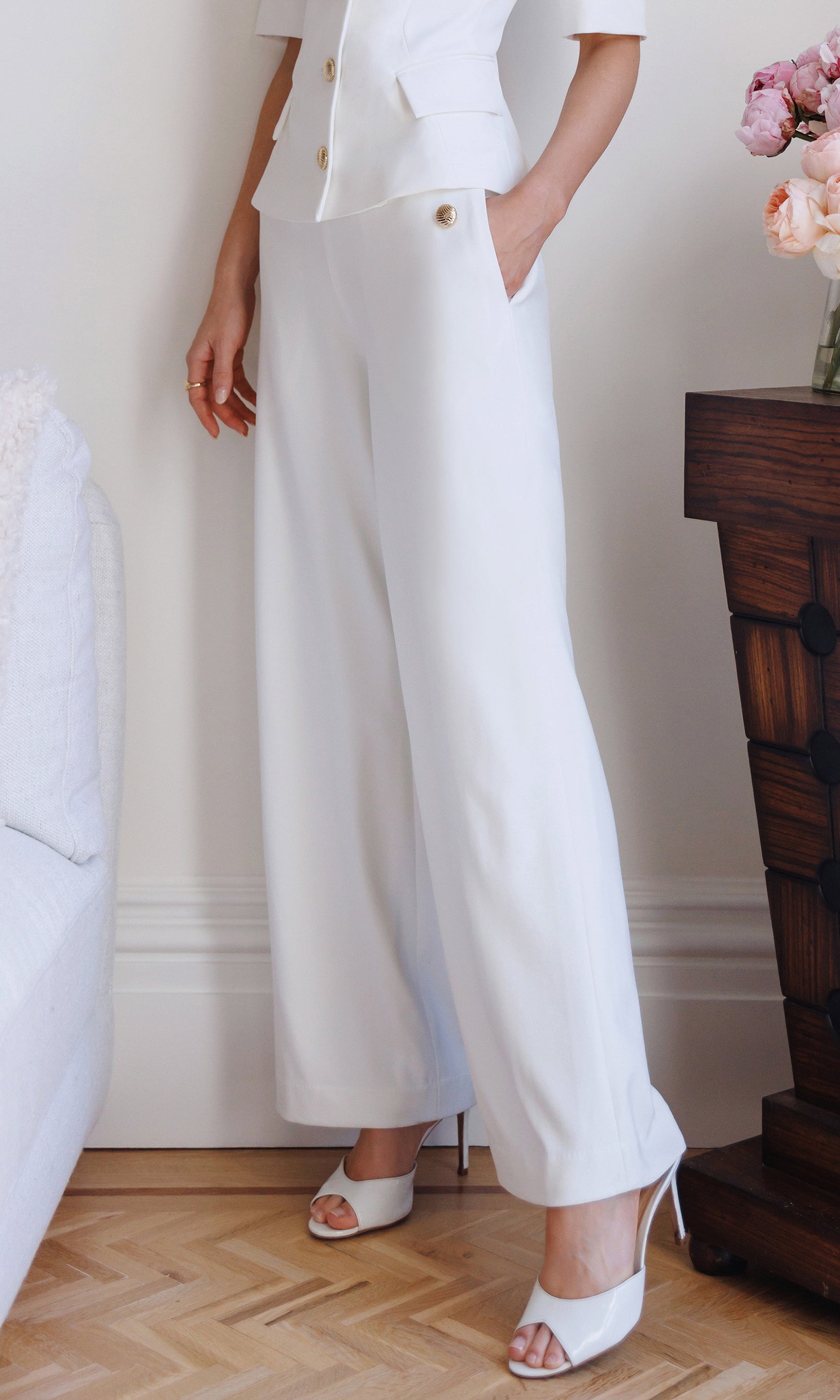 Person wearing a white outfit with wide-leg pants in an indoor setting.