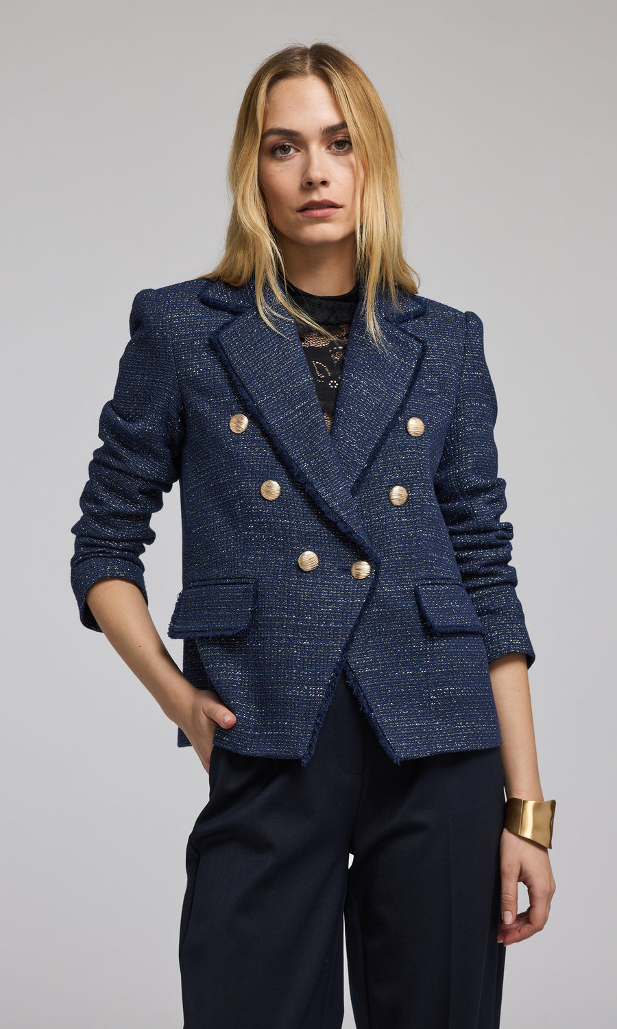 The image features a navy tweed blazer with striking gold buttons, exemplifying classic fashion elegance.