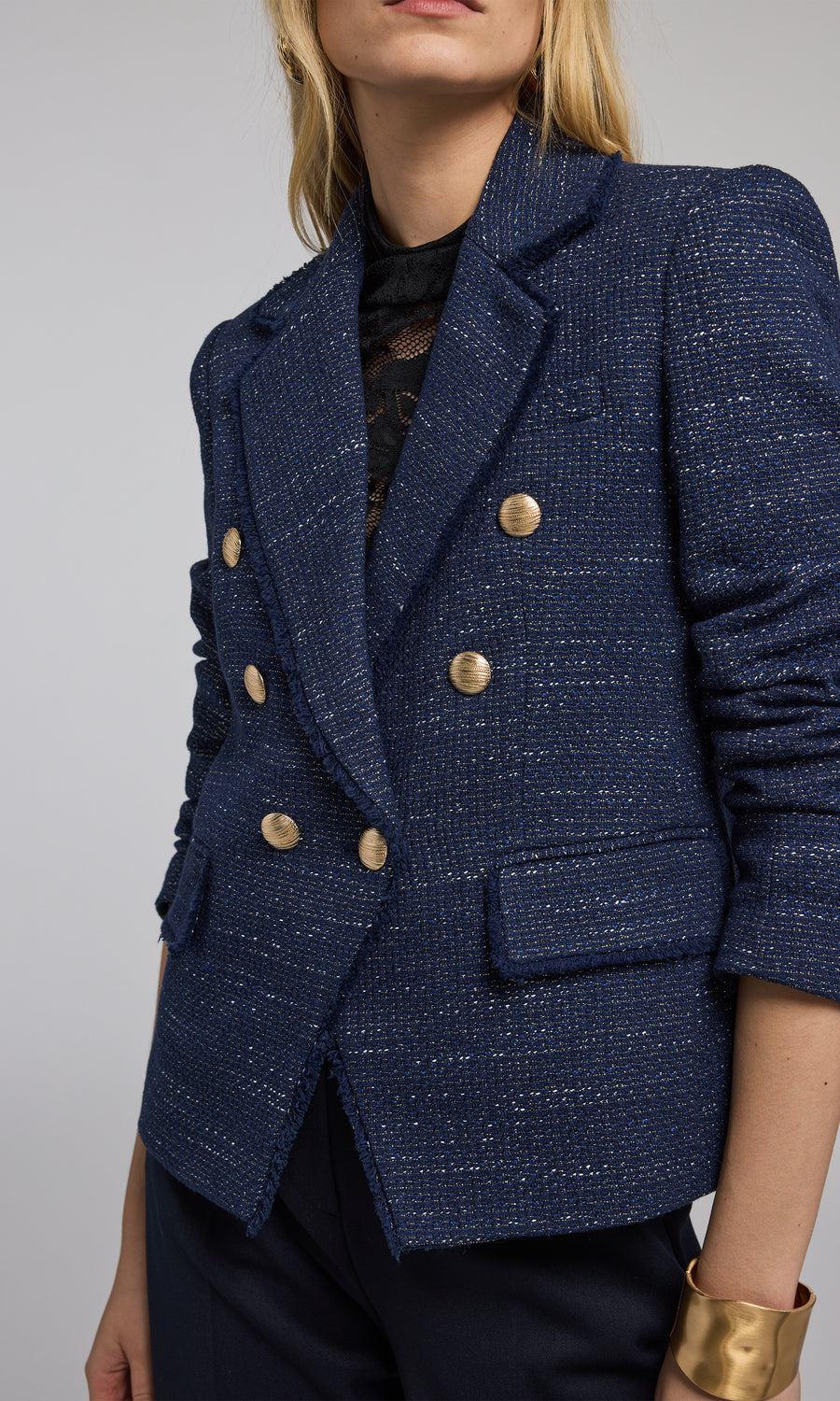 The image features a navy tweed blazer with striking gold buttons, exemplifying classic fashion elegance.