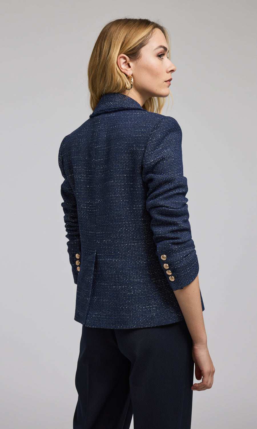 The image features a navy tweed blazer with striking gold buttons, exemplifying classic fashion elegance.