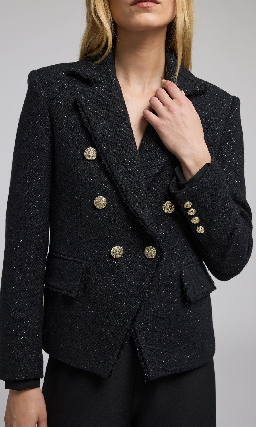 A model showcases a stylish black tweed blazer, exuding elegance and sophistication in a contemporary setting.