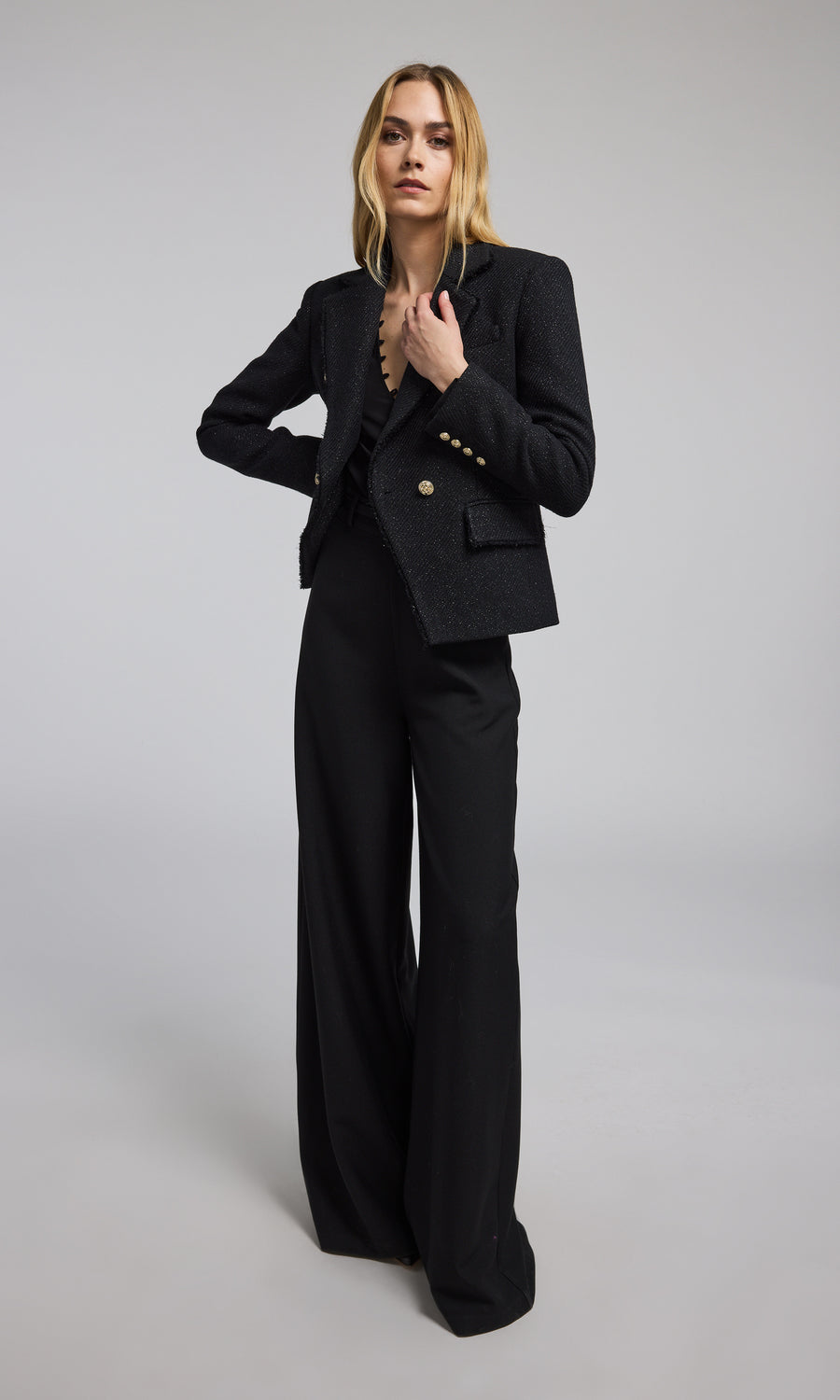 A model showcases a stylish black tweed blazer, exuding elegance and sophistication in a contemporary setting.