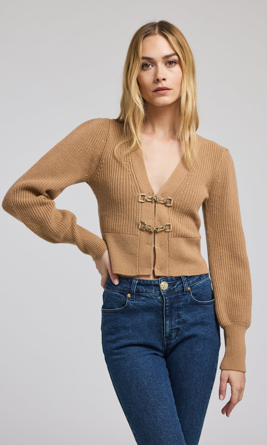 This cropped camel cardigan features a soft, ribbed knit texture, offering both comfort and a chic look for various outfits.