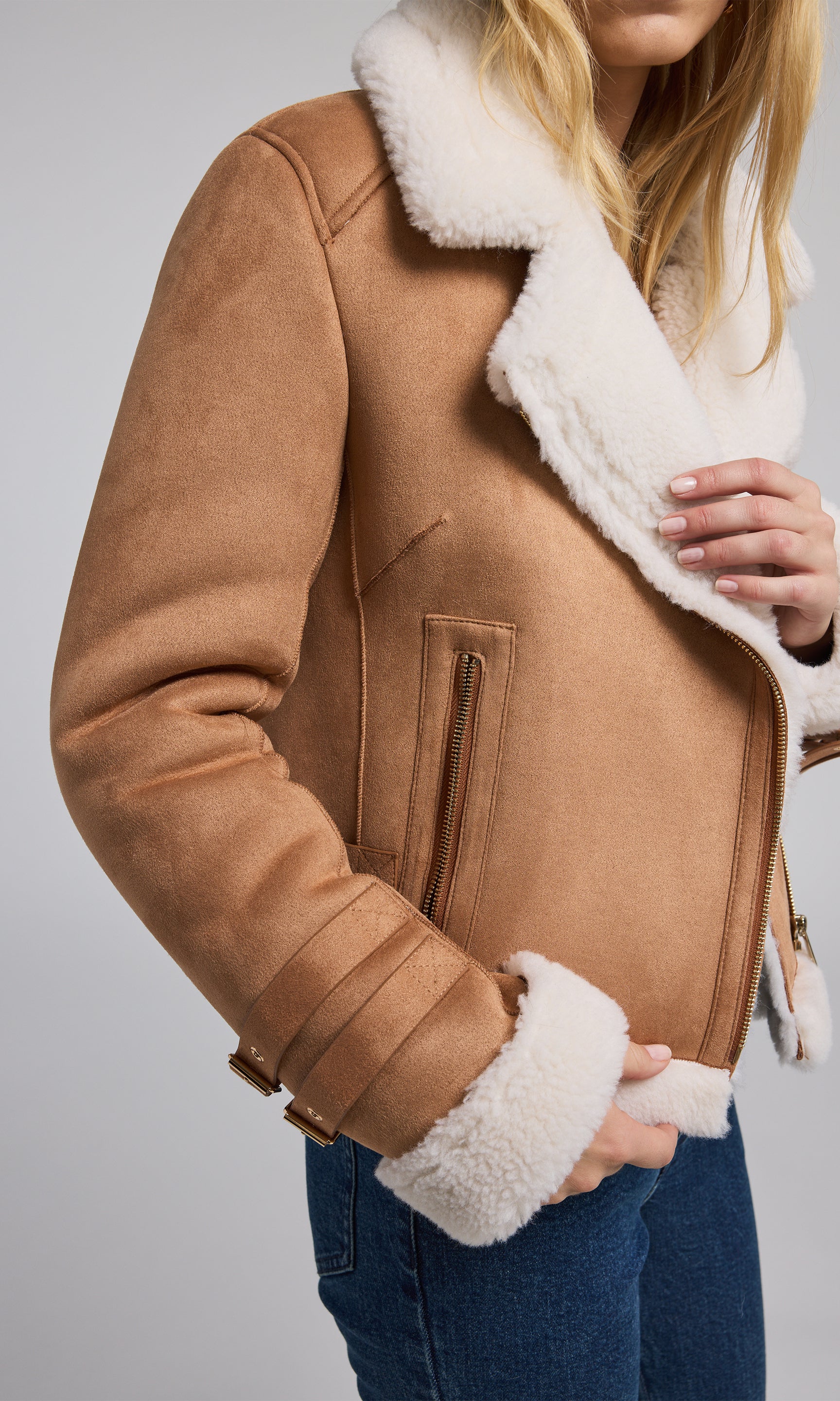 The image features a tan vegan suede shearling Moto jacket, highlighting its sleek and fashionable appearance.