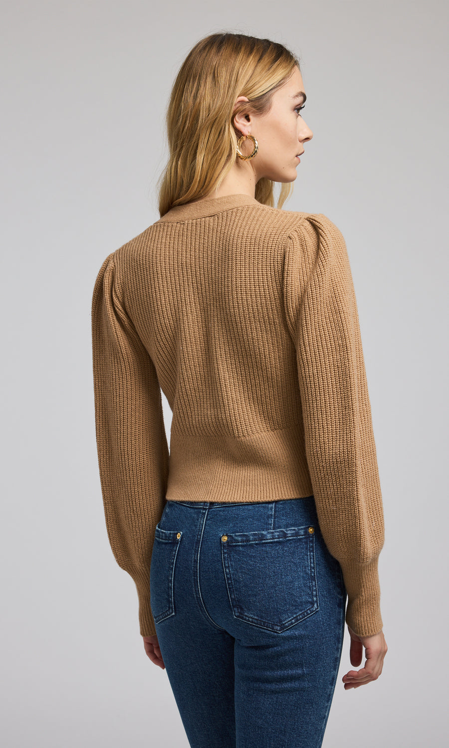 This cropped camel cardigan features a soft, ribbed knit texture, offering both comfort and a chic look for various outfits.