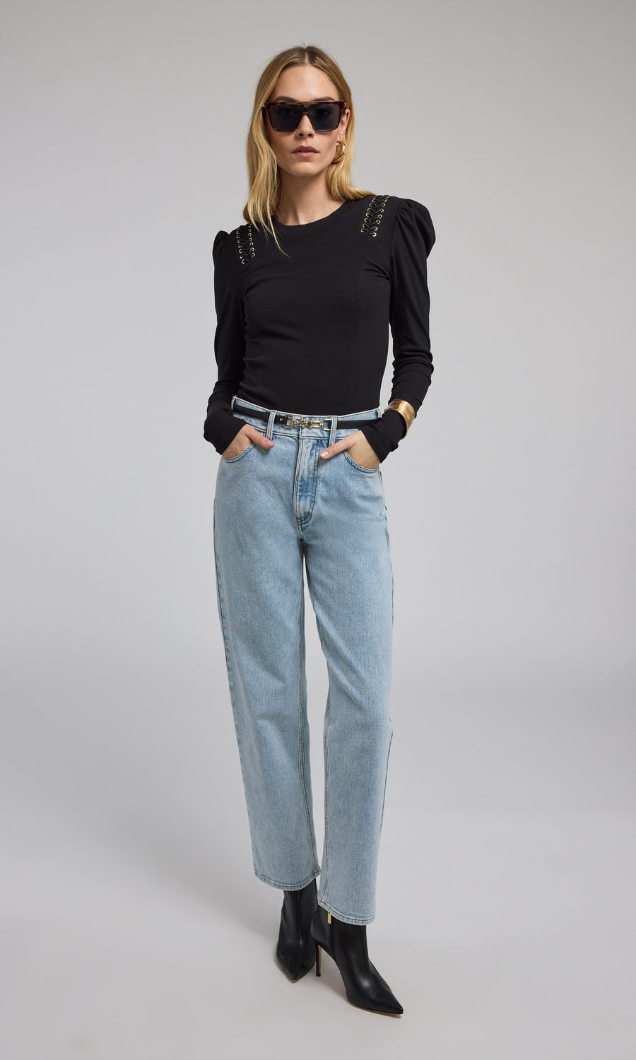 A model is seen wearing light blue denim pants, highlighted by a fashionable black vegan leather belt.