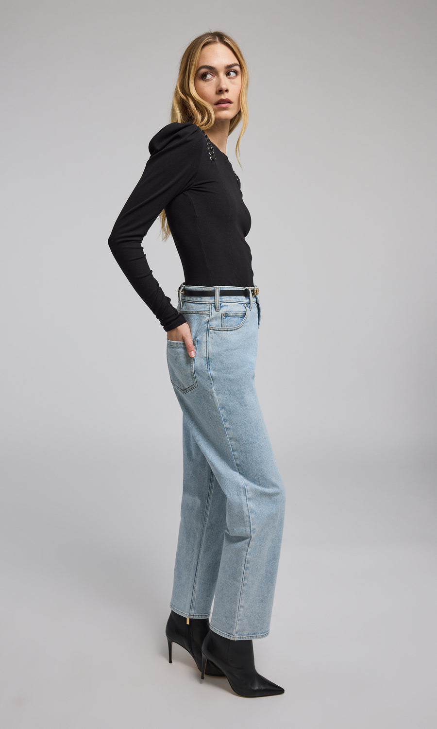 A model is seen wearing light blue denim pants, highlighted by a fashionable black vegan leather belt.