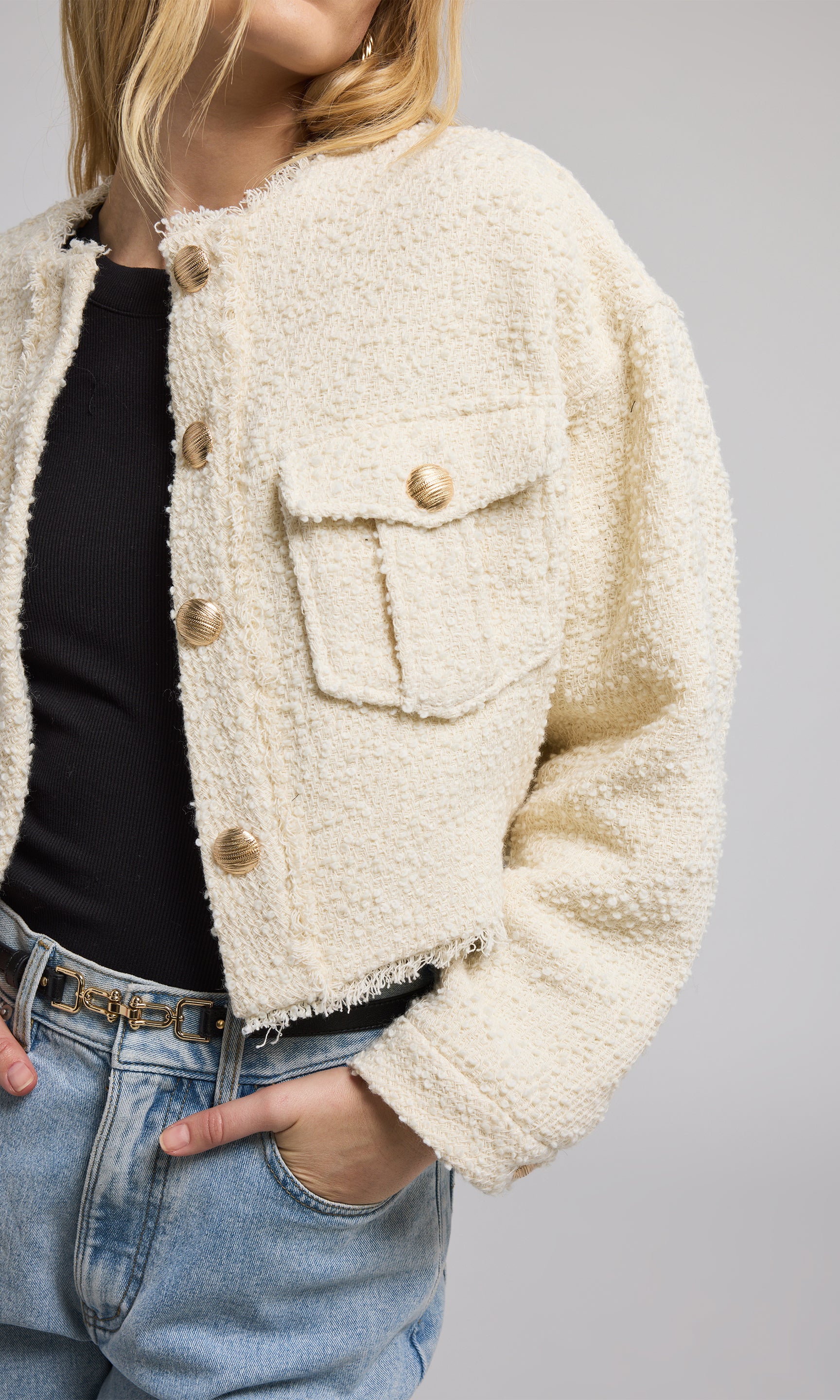 A cropped cream tweed bomber jacket crafted from soft, fluffy material, showcasing a stylish and cozy design.