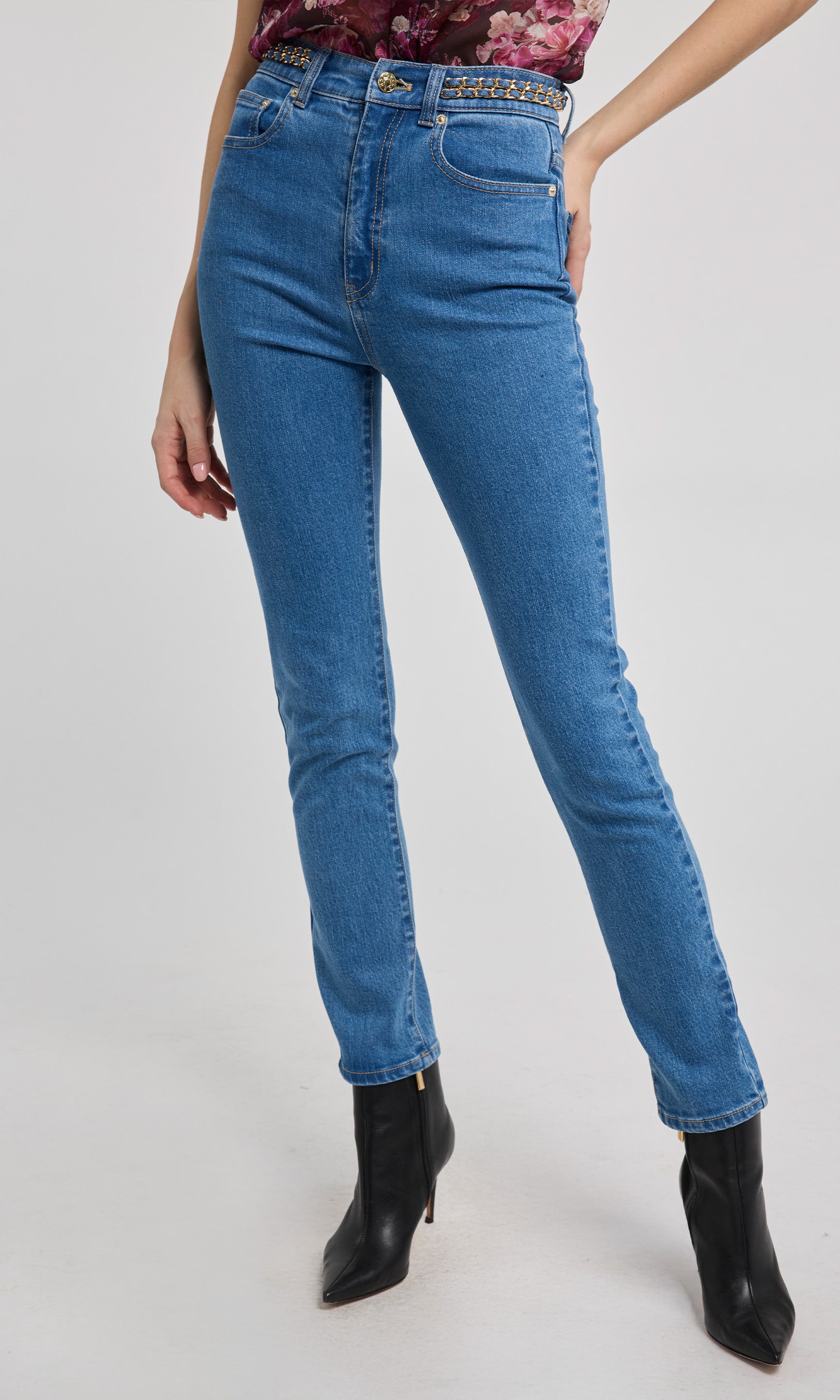 Person wearing blue jeans and black boots on a white background