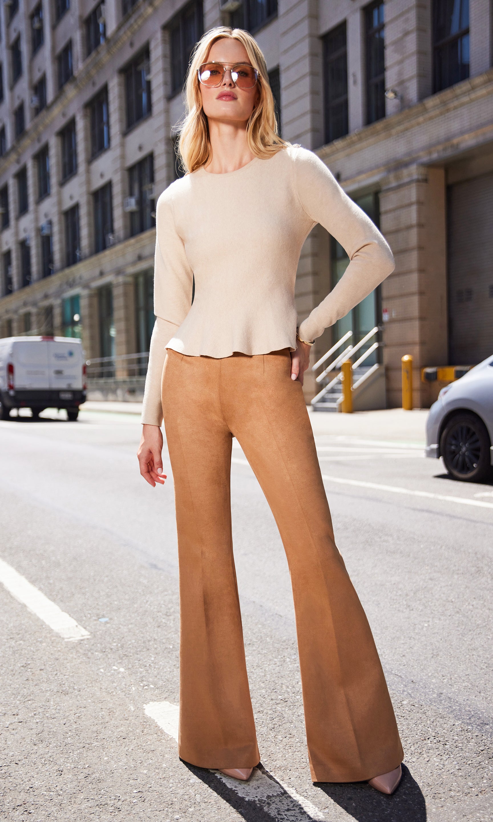 Full body view of the model in the Panache Peplum Sweater and camel wide-leg pants, walking outdoors in natural sunlight.