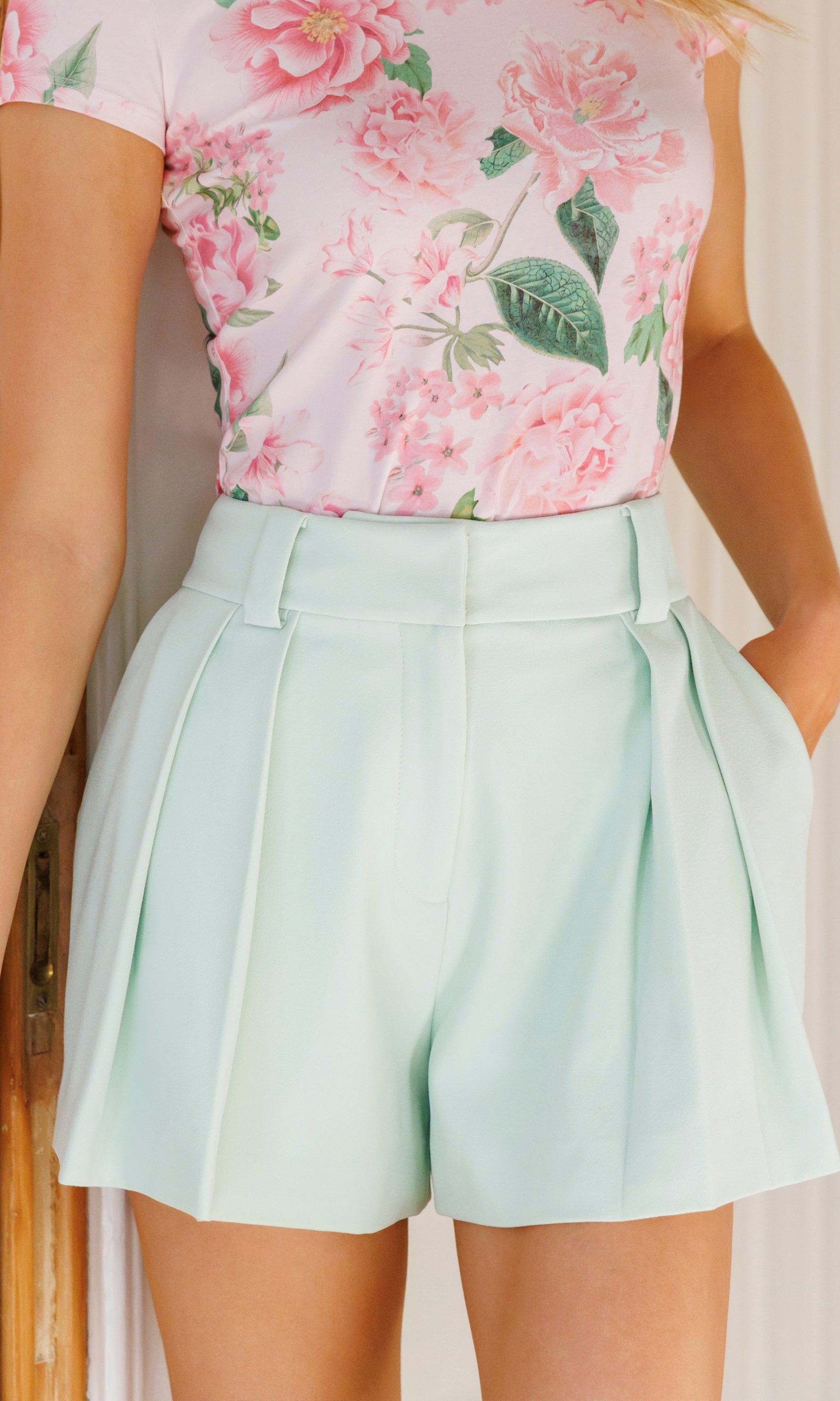 Model wears the Willa Lightweight Crepe Shorts in mint in a close-up front view, highlighting the clean waistband, pleated front, and smooth crepe texture.