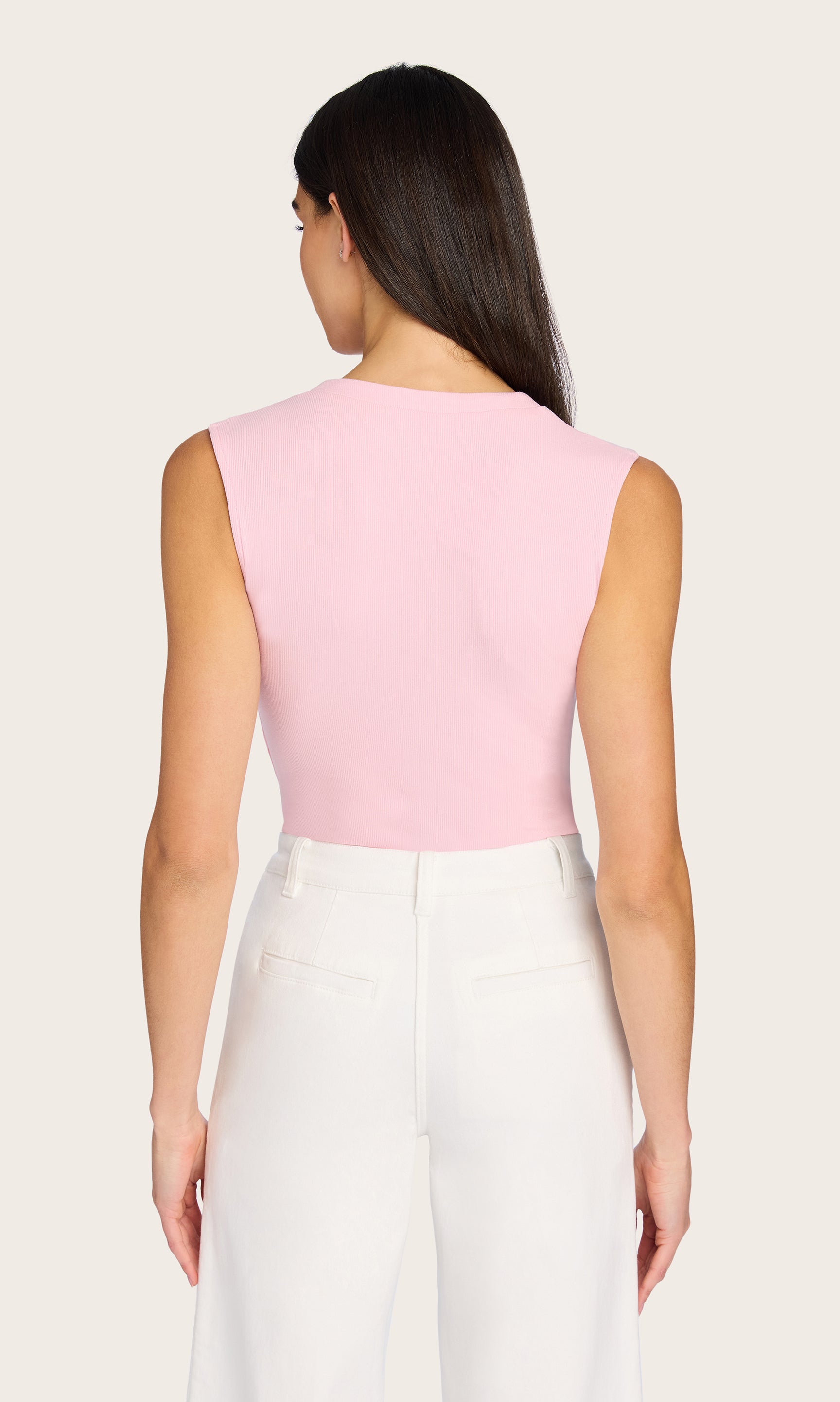 Rear view of the Zoelle Rib Tank in pink, styled with white pants and showcasing the clean back cut and slim silhouette.