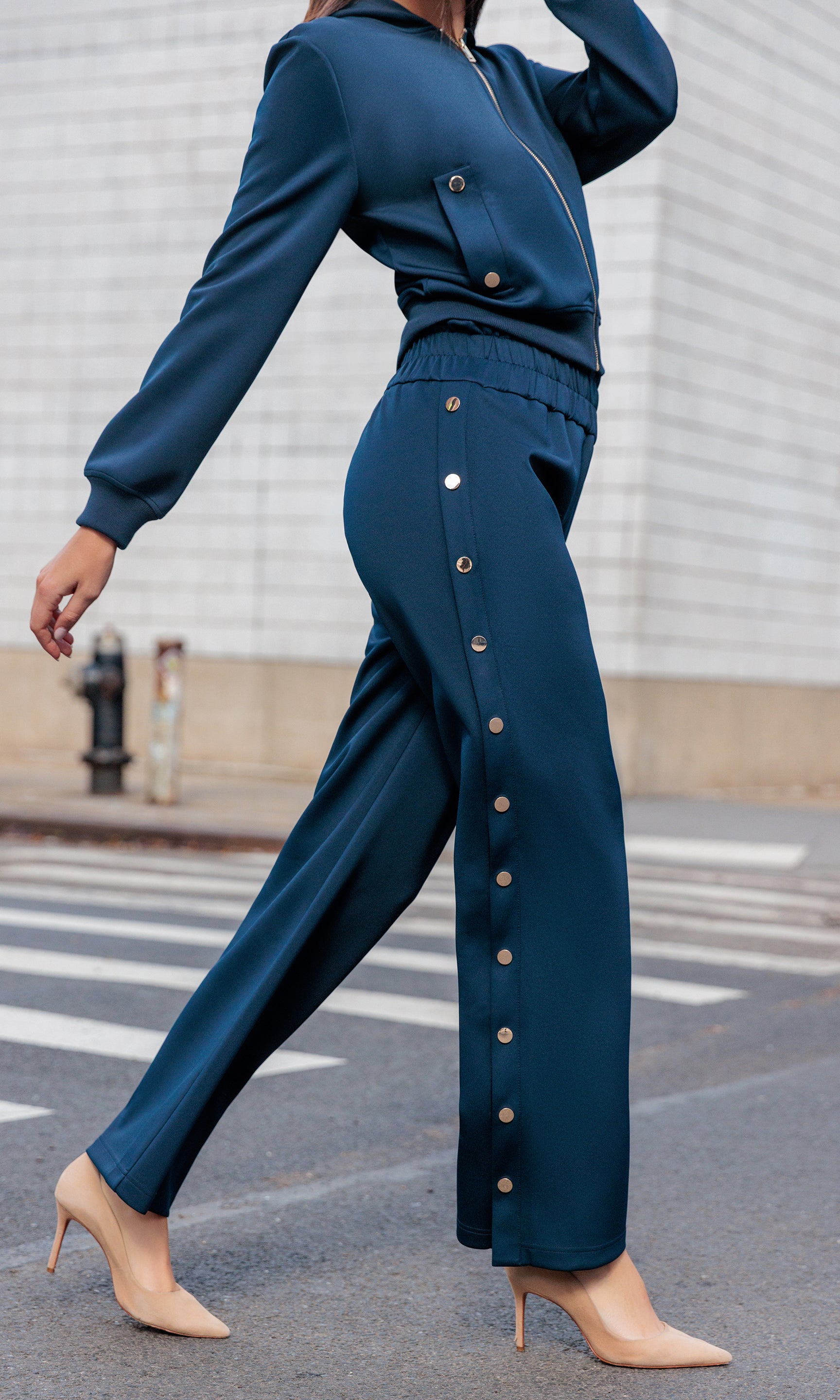 Person wearing a blue outfit with button details walking on a street.