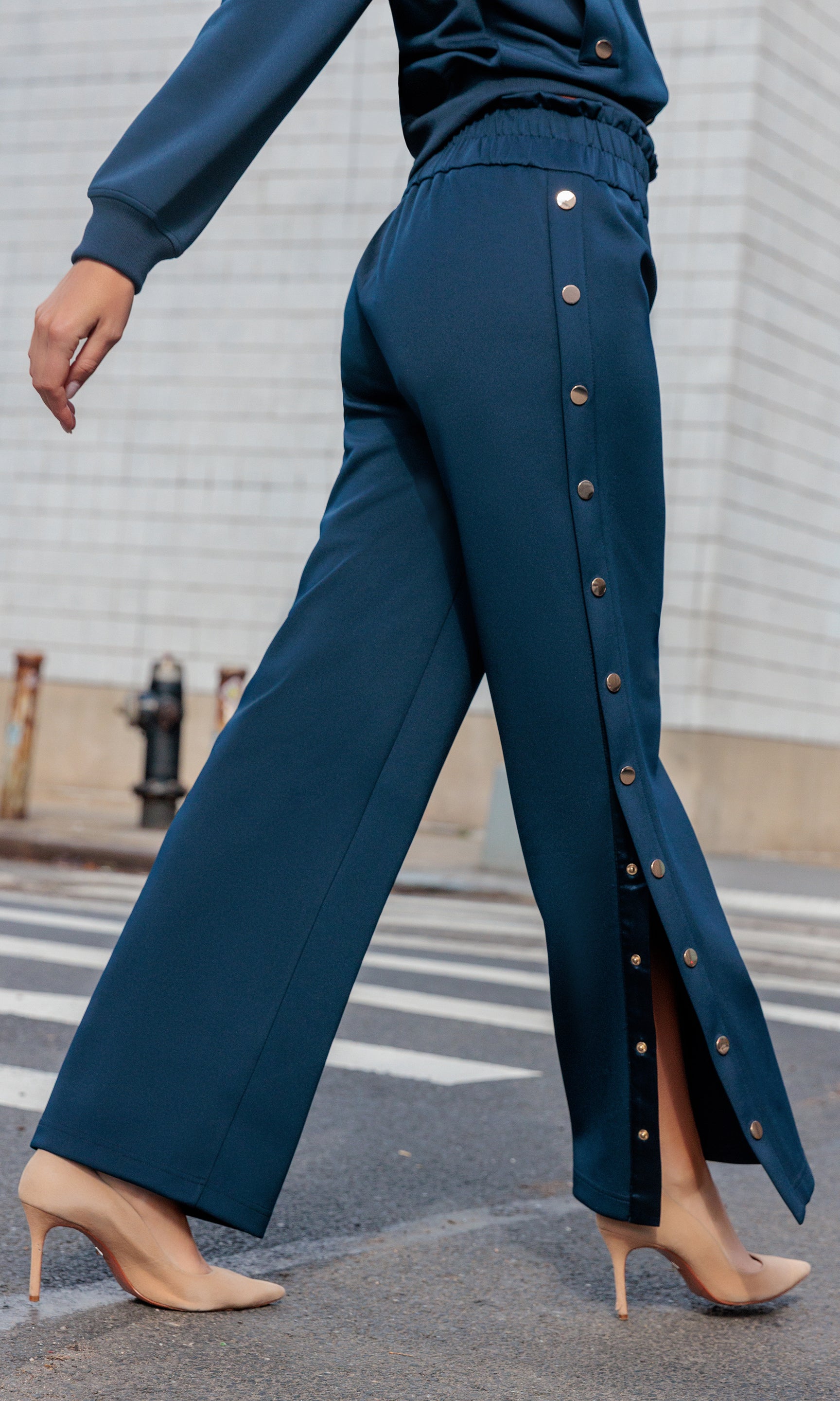 Navy blue pants with button details worn by a person on a city street.