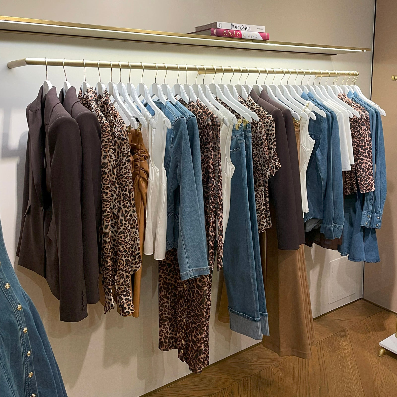 Clothing rack with various Generation love fall jackets and pants hanging on a white wall.