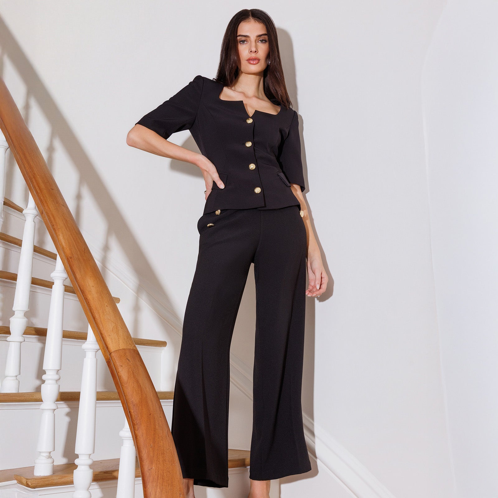 Woman in a black outfit standing in front of a staircase