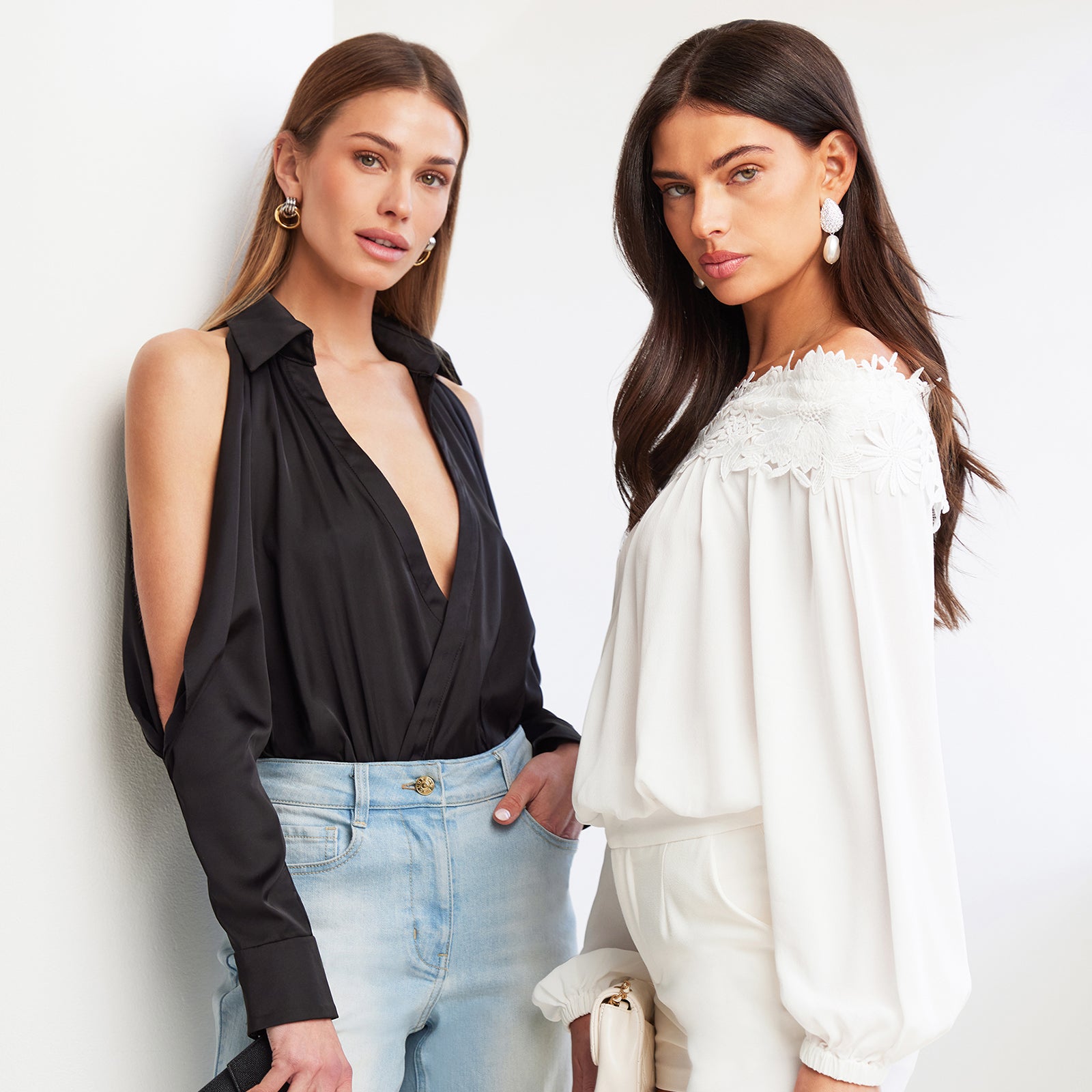 image of two models standing side by side, on the left model is wearing a Dee bodysuit in black with blue jeans, on the right model is wearing an off shoulder Merla blouse in white with white shorts