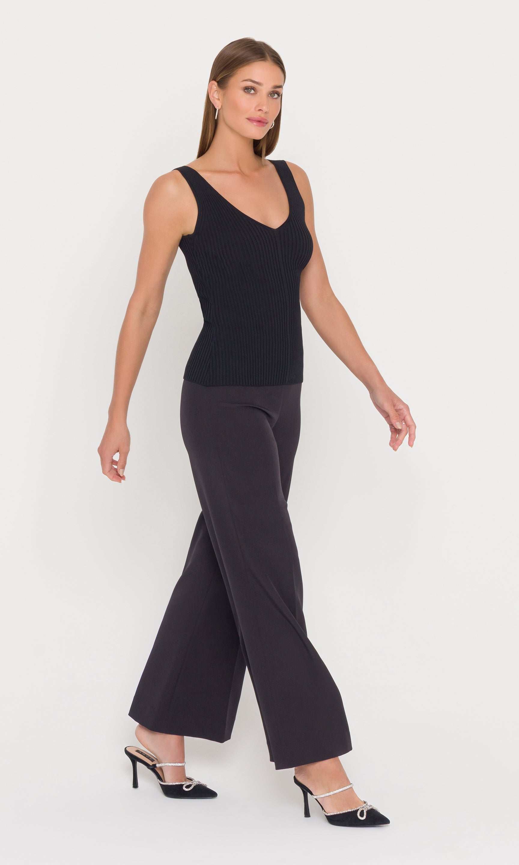 Woman wearing a black sleeveless top and wide-leg pants on a white background