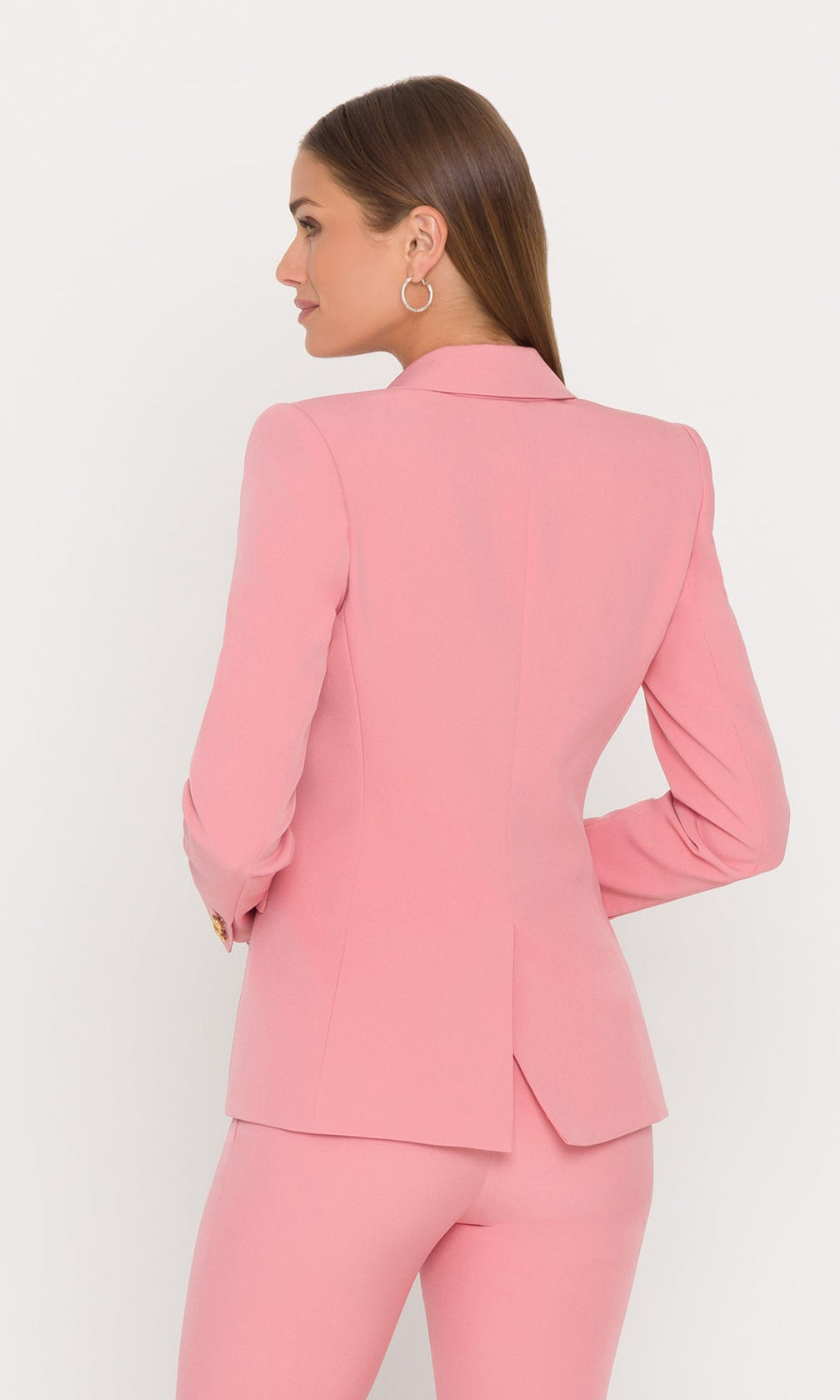 back view of model wearing a pink blazer with gold buttons and matching pants