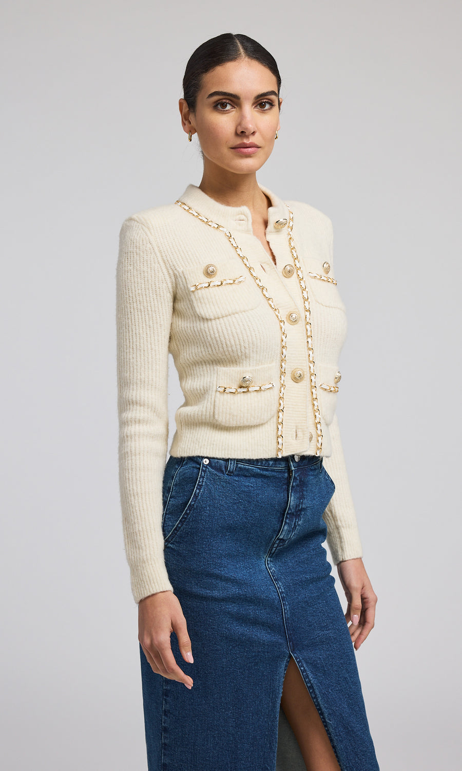 A buttoned front ivory chain cardigan, exemplifying warmth and elegance, perfect for layering in cooler weather.