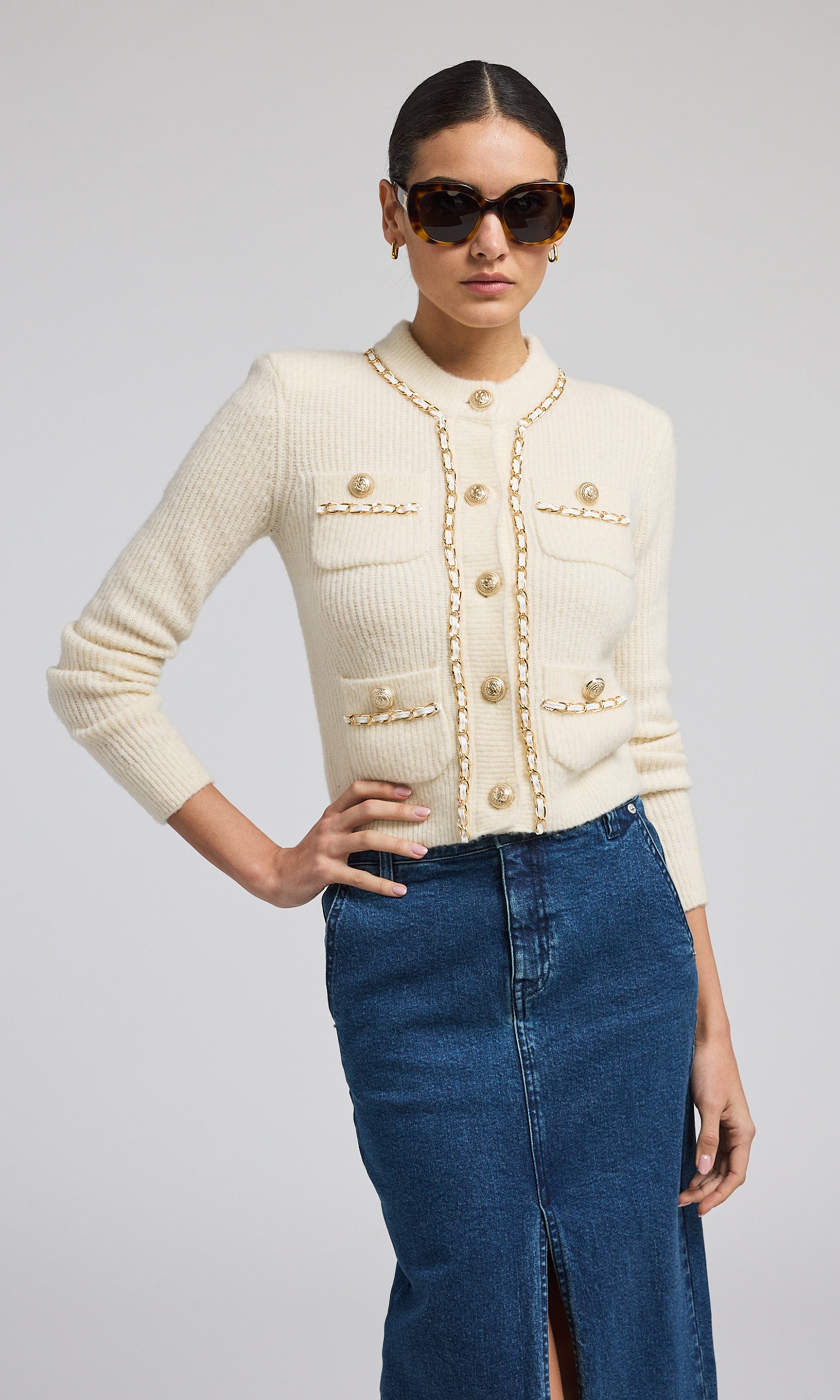 A buttoned front ivory chain cardigan, exemplifying warmth and elegance, perfect for layering in cooler weather.